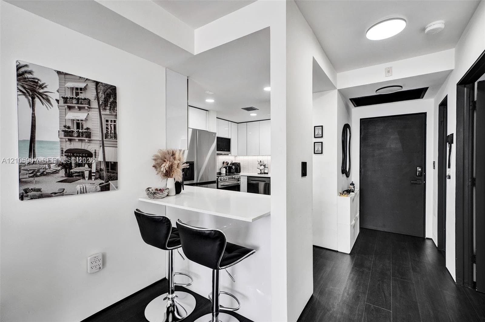Interior entry featuring dark wood-finish flooring, a built-in white peninsula counter, flat-panel white cabinetry, and stainless steel appliances