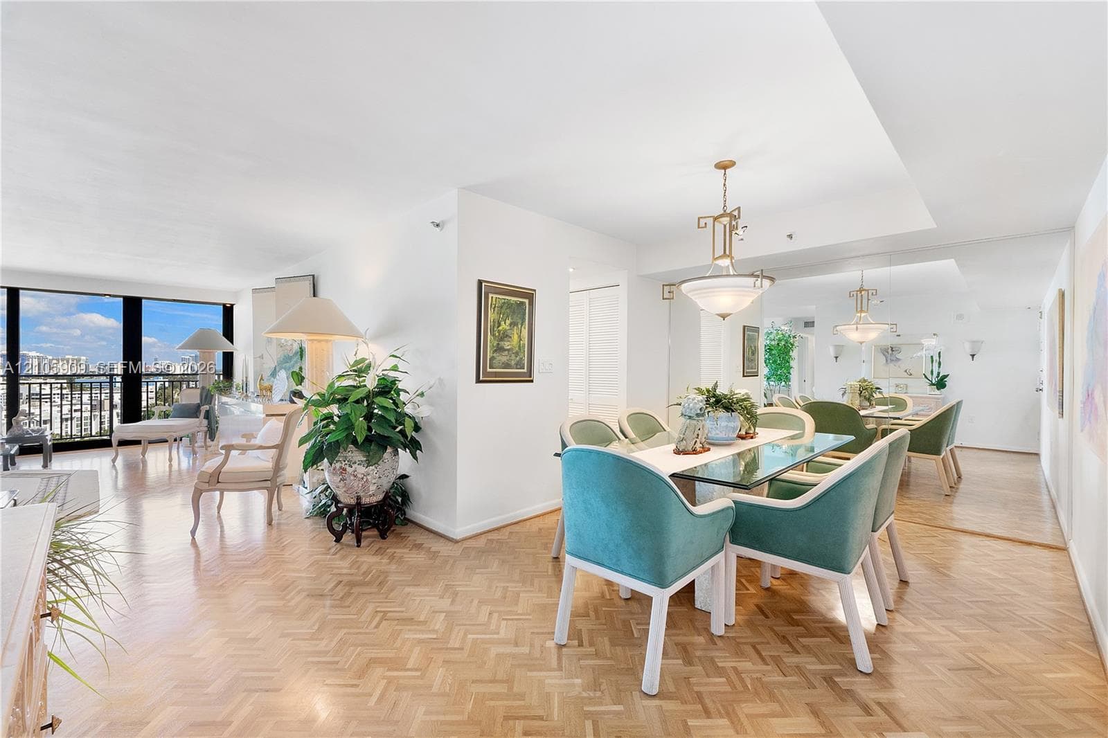 Open-concept living space featuring herringbone-pattern wood flooring, floor-to-ceiling windows, a mirrored wall accent, and a recessed ceiling with a decorative pendant light fixture