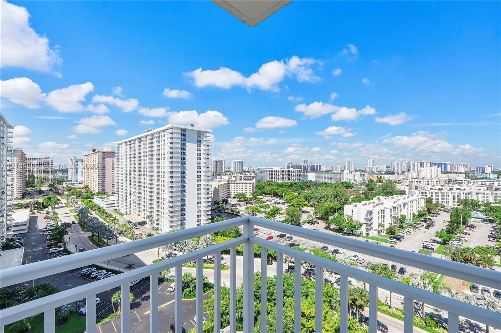 Elevated balcony featuring a white metal railing and expansive urban scenery
