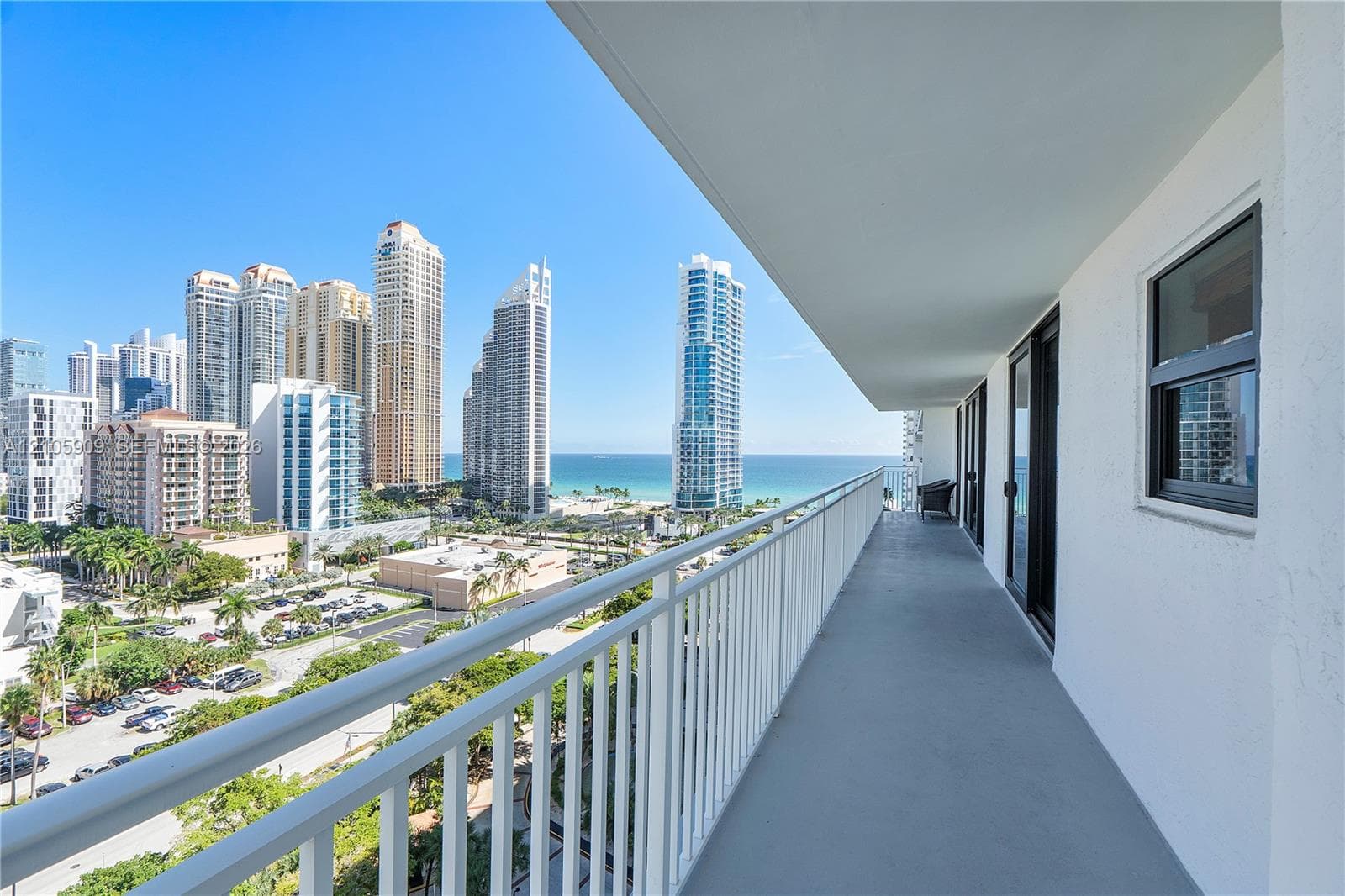 Covered outdoor balcony with a white metal railing and sliding glass doors