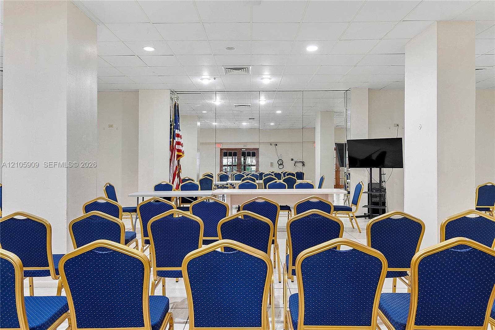 Open-concept interior space featuring high ceilings, recessed lighting, tile flooring, and mirrored wall panels
