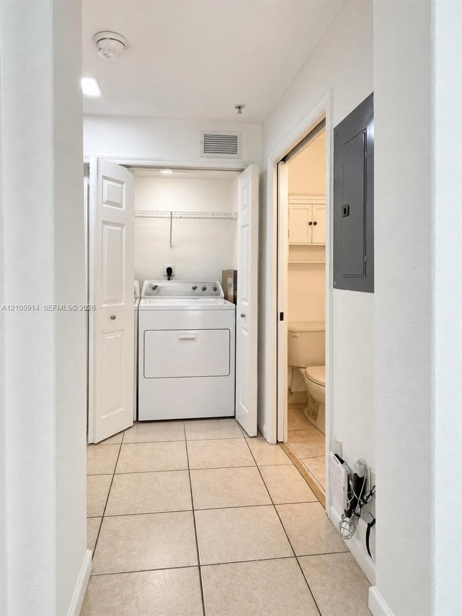 Laundry area featuring tile flooring, built-in wire shelving, and bi-fold closet doors