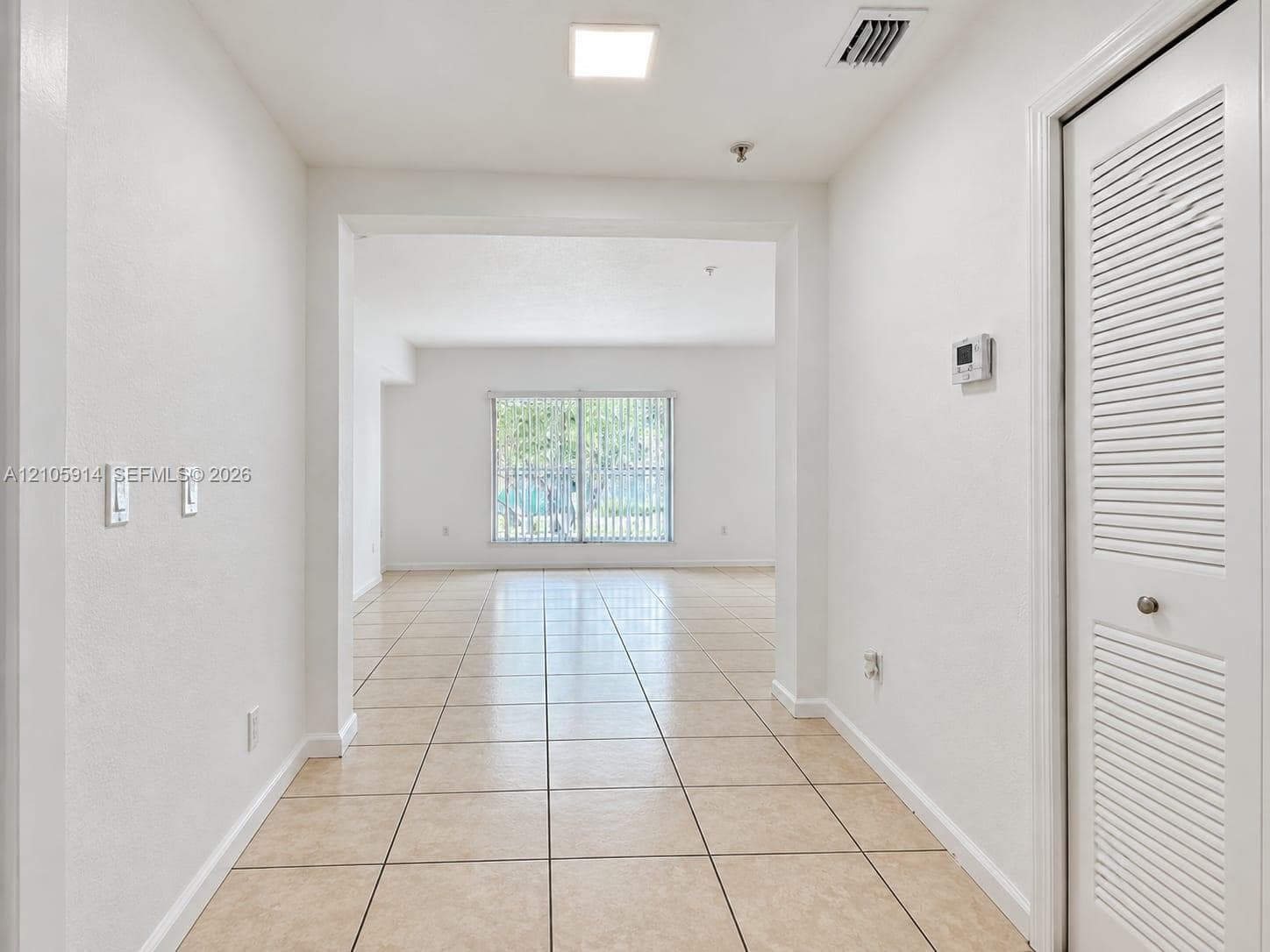 Interior space featuring large-format ceramic tile flooring, neutral wall finishes, recessed ceiling lighting, and a closet with bifold louvered doors
