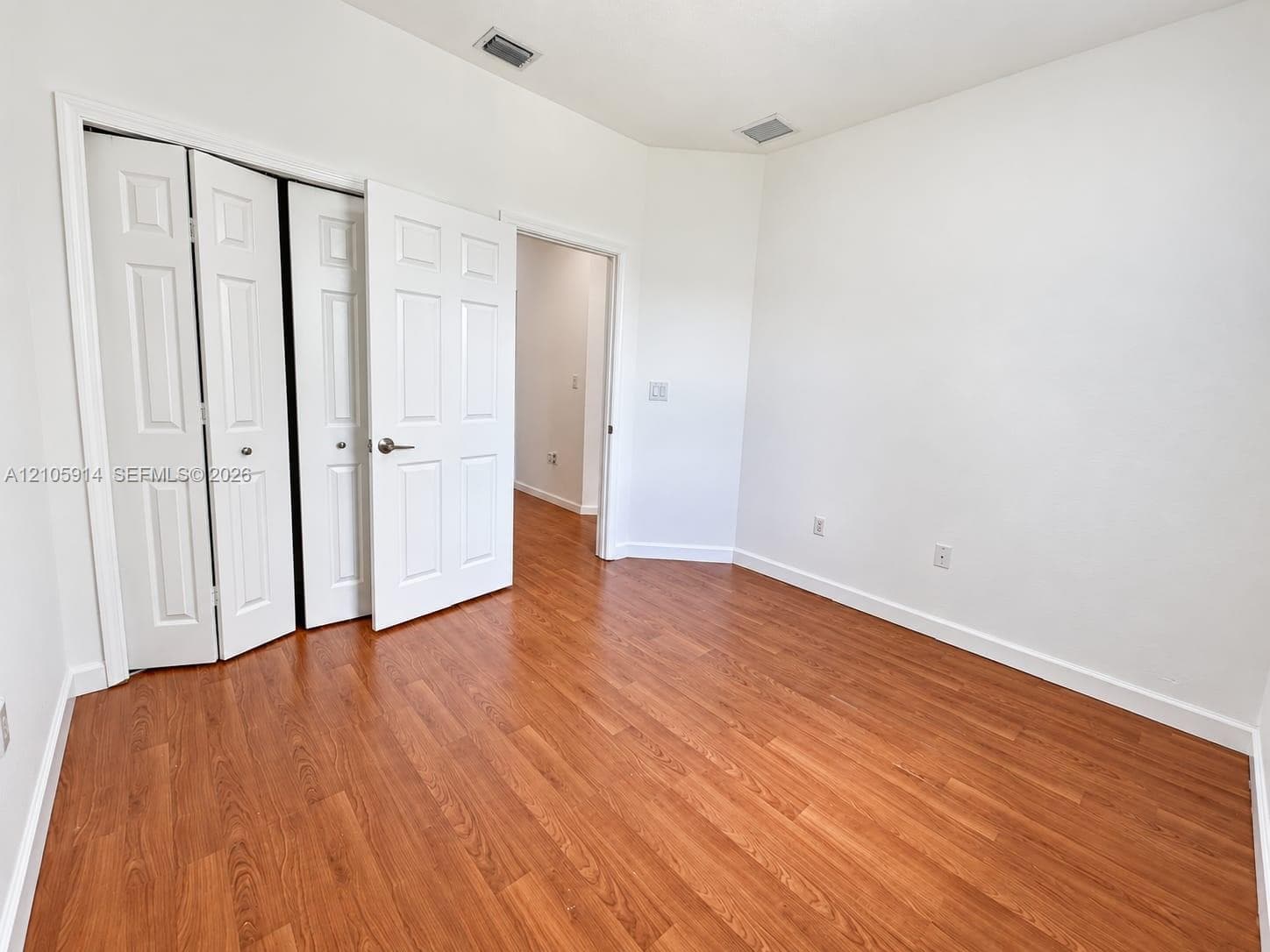 Neutral wall palette with wood-finish flooring and paneled bi-fold closet doors