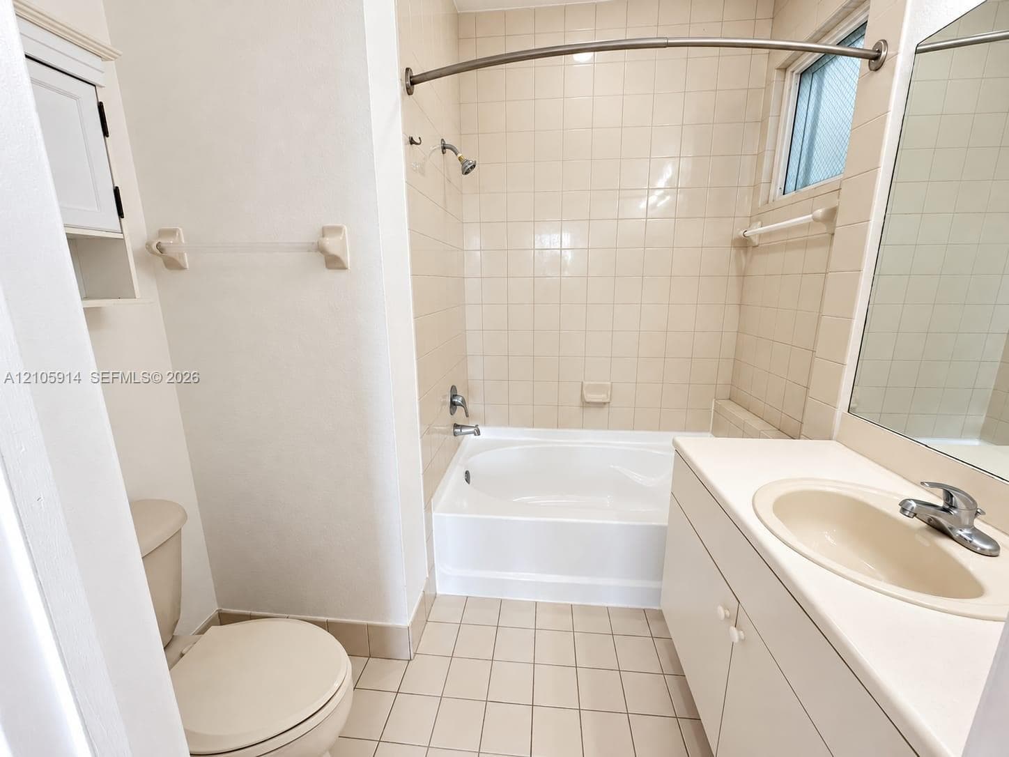 Bathroom featuring a white vanity cabinet with an integrated sink, tiled tub and shower surround, curved shower rod, and ceramic tile flooring