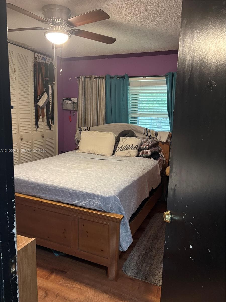 Bedroom featuring wood-finish flooring, a ceiling fan with integrated lighting, and louvered-panel closet doors