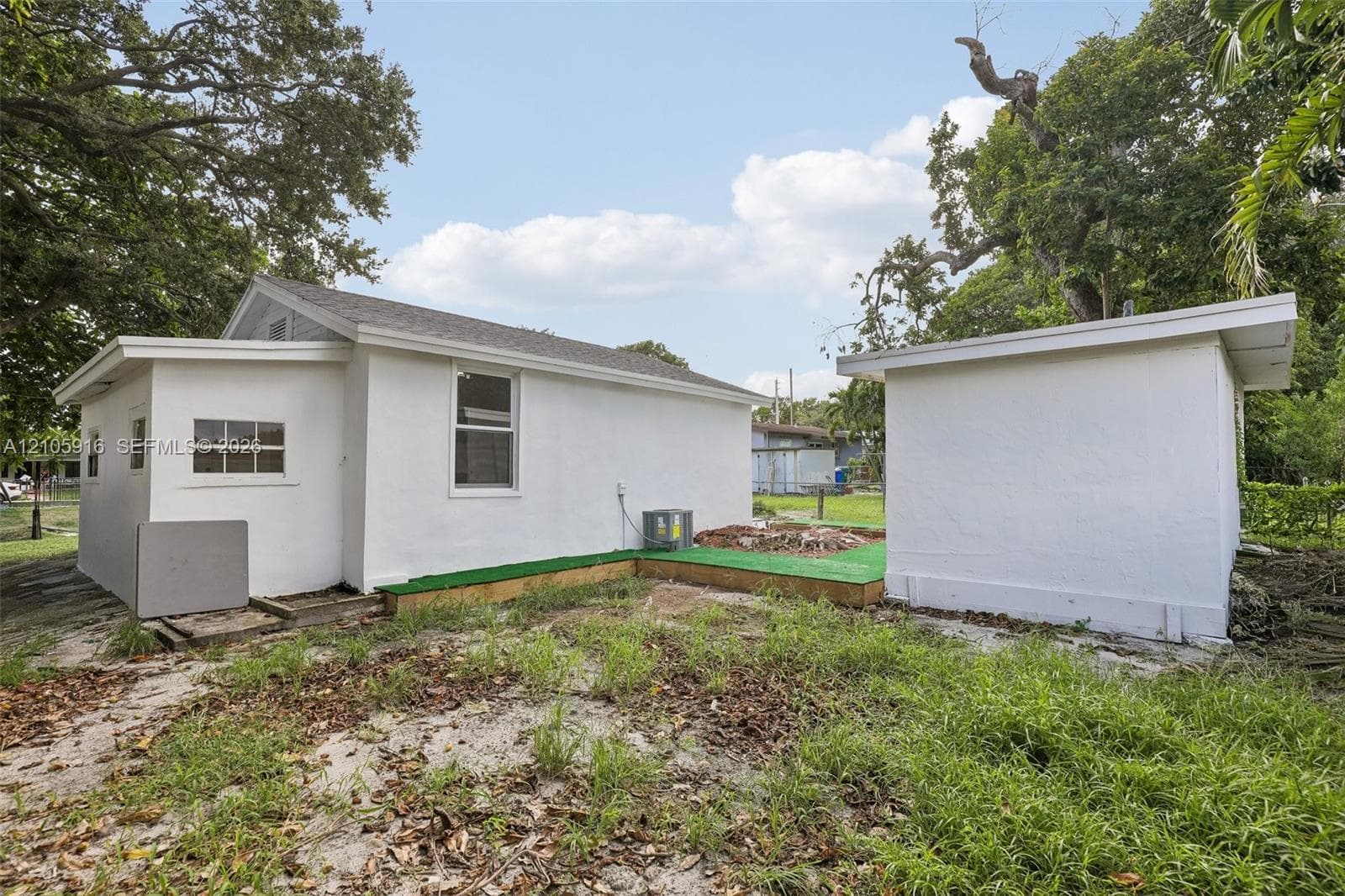 White stucco exterior featuring a detached outbuilding and a raised platform deck