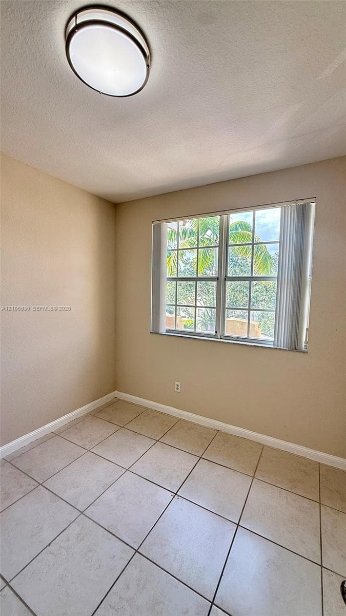 Interior space featuring tile flooring, a multi-pane window with vertical blinds, and a circular flush-mount ceiling light fixture