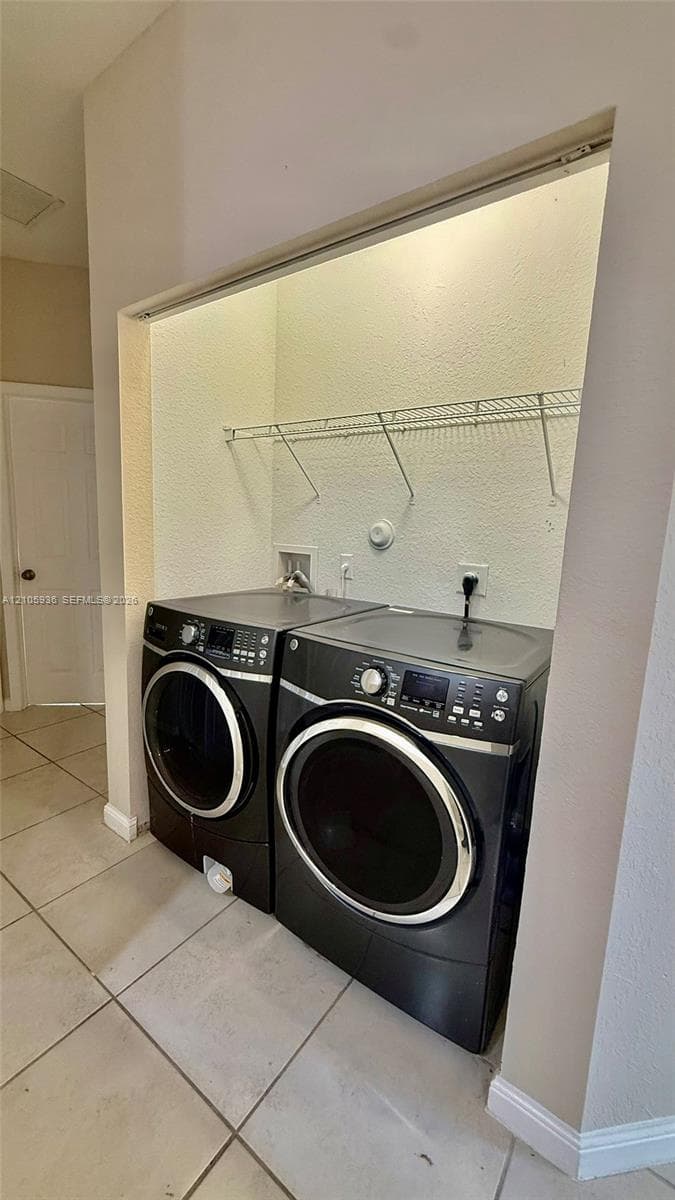 Laundry alcove featuring ceramic tile flooring and white wire shelving