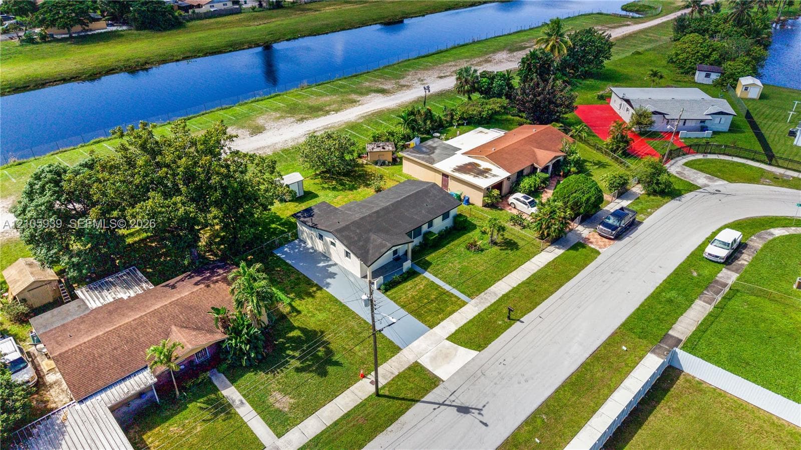 Aerial perspective featuring residential lots with canal frontage, asphalt paved streets, concrete driveways, and mature landscaping