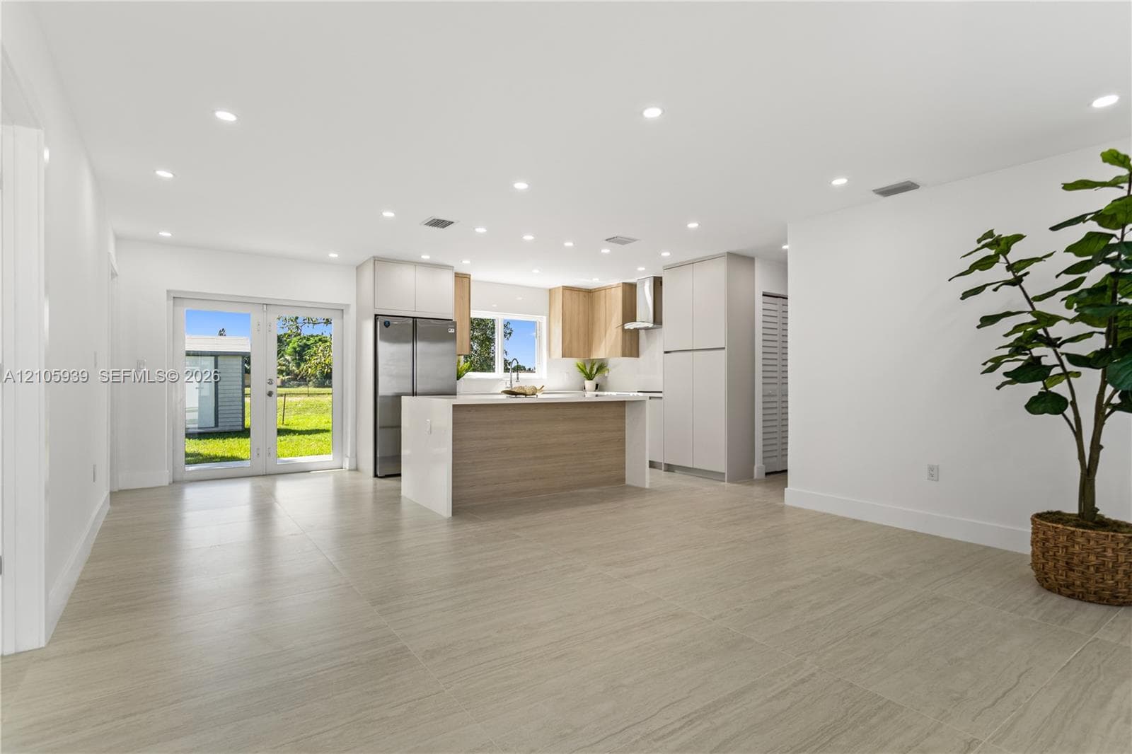 Kitchen featuring a center island, light-finish cabinetry, stainless steel refrigerator, recessed lighting, and large-format tile flooring