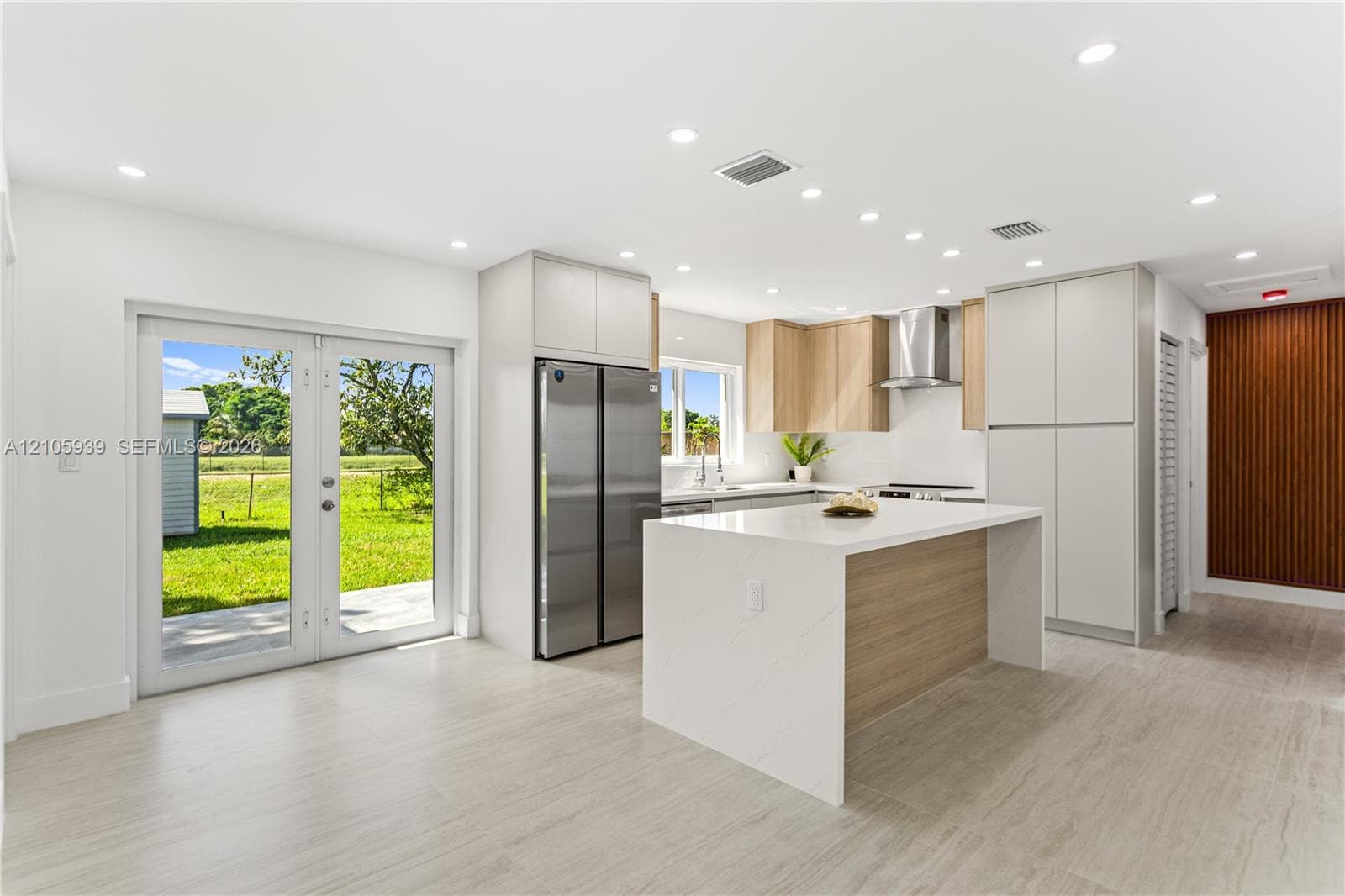 Kitchen featuring a central island with a solid surface countertop, stainless steel refrigerator, recessed lighting, double glass doors, and tile flooring
