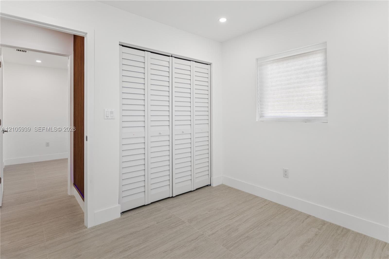 Room featuring wood-finish flooring, white walls, louvered bi-fold closet doors, and recessed lighting