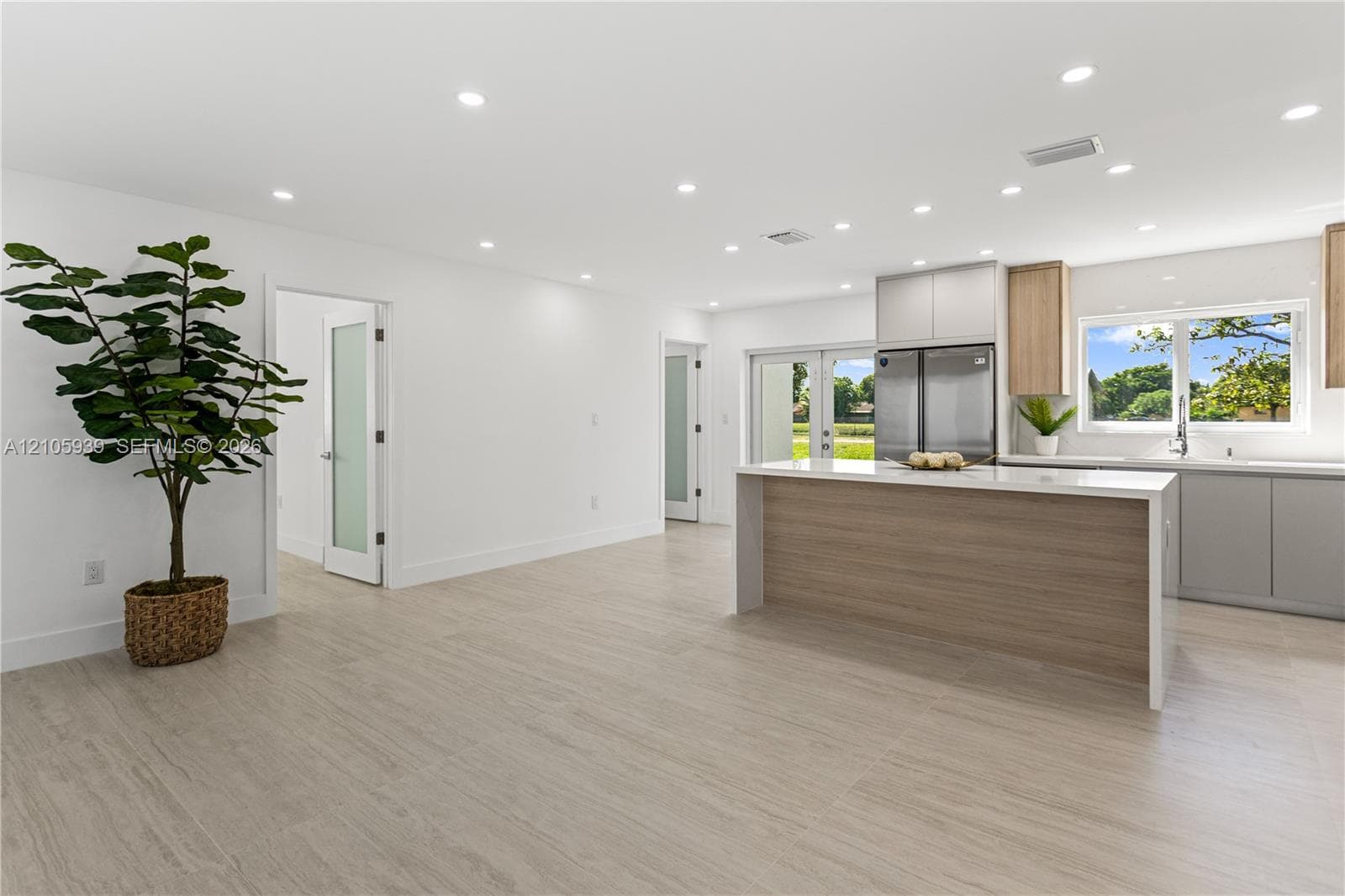 Open concept space featuring light-toned wood-finish flooring, recessed lighting, and a kitchen island with a neutral-toned base