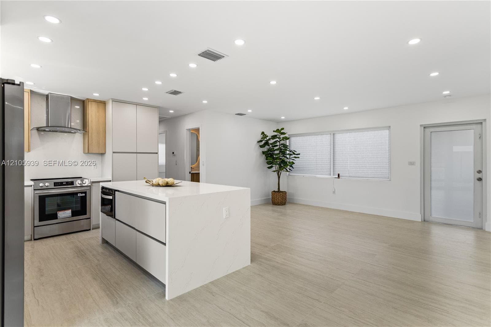 Kitchen featuring a center island with a stone-finish countertop, stainless steel appliances, flat-panel cabinetry, recessed lighting, and wood-finish flooring