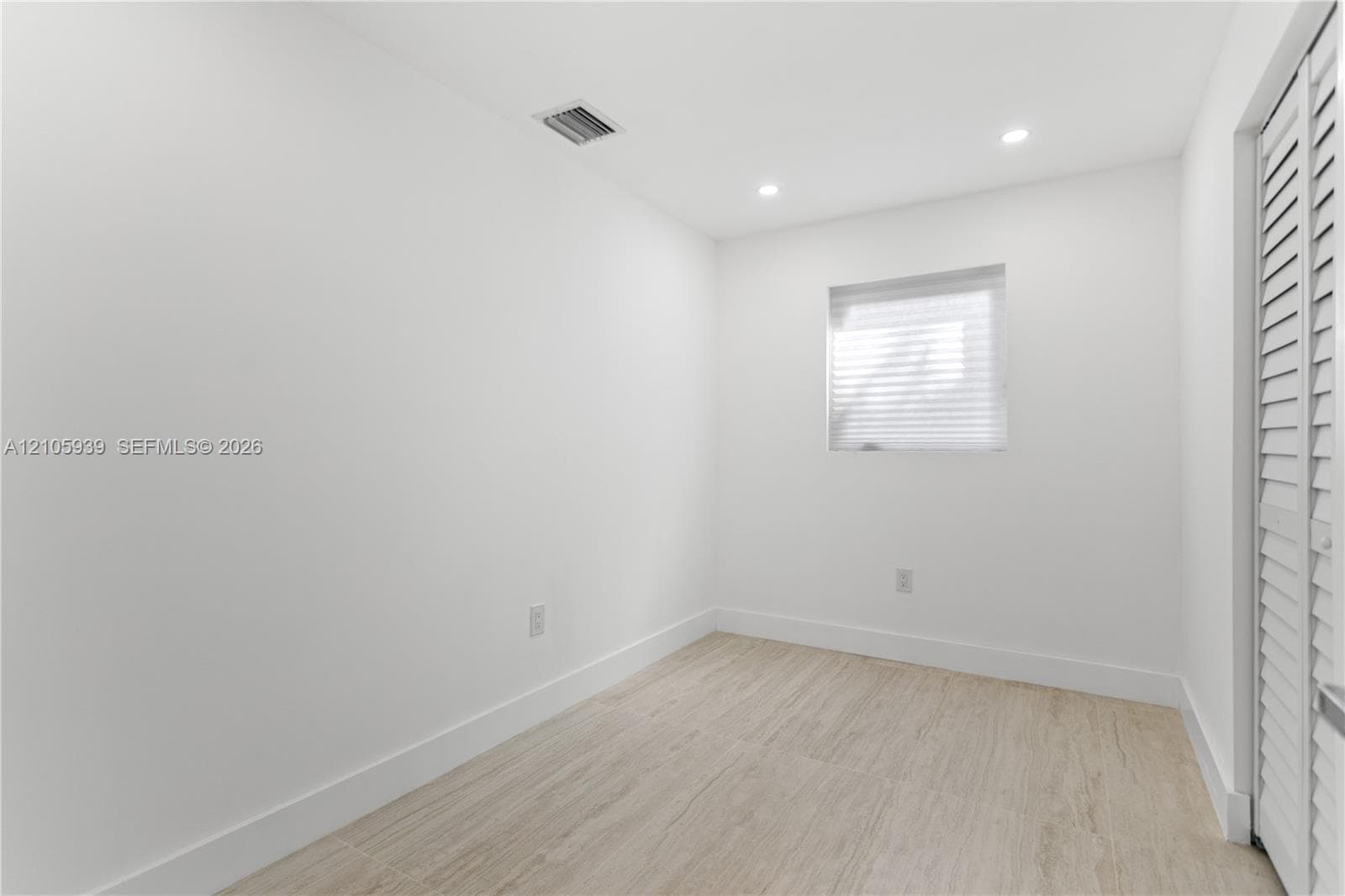 Interior space featuring wood-finish tile flooring, recessed ceiling lighting, and louvered closet doors