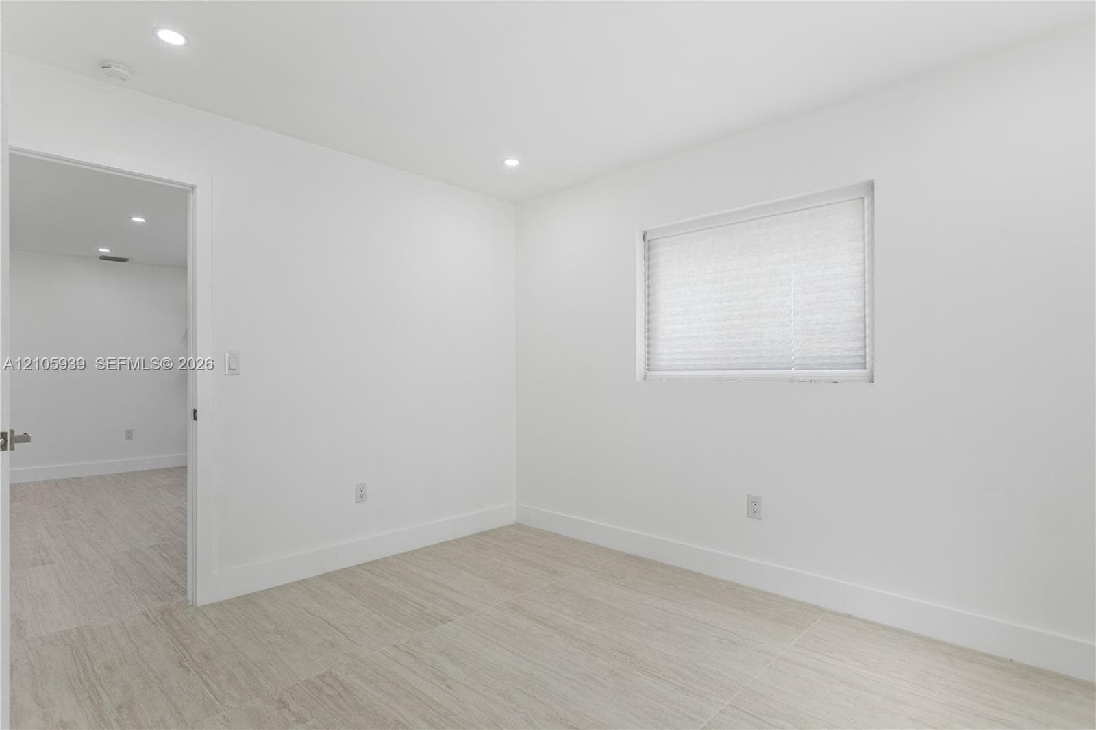 Neutral interior featuring wood-finish flooring, recessed lighting, and a window with a pleated shade