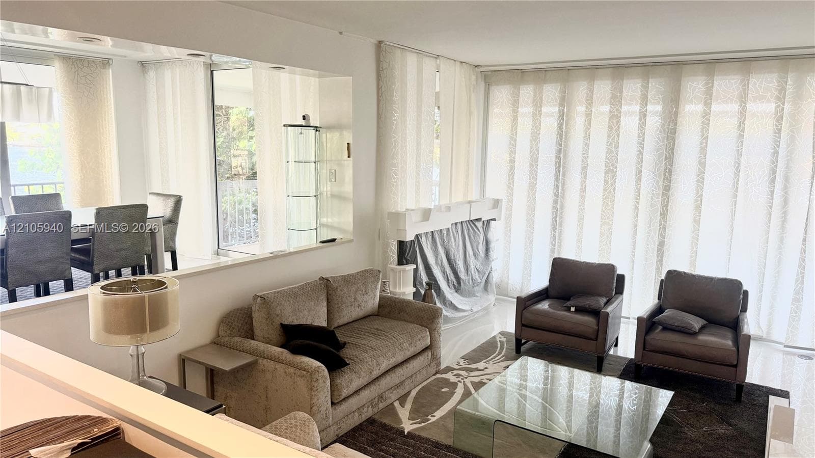 Large-scale wall mirror, neutral tile flooring, and floor-to-ceiling sliding glass panels