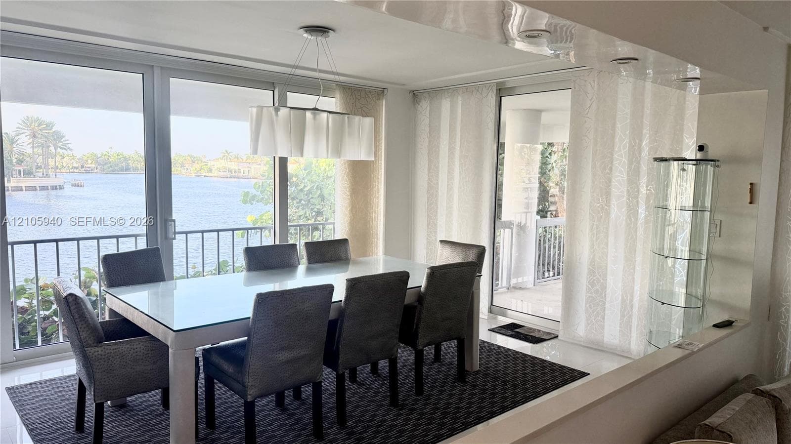 Floor-to-ceiling glass windows, recessed ceiling lighting, built-in display cabinetry, and polished flooring featuring direct water access to a balcony