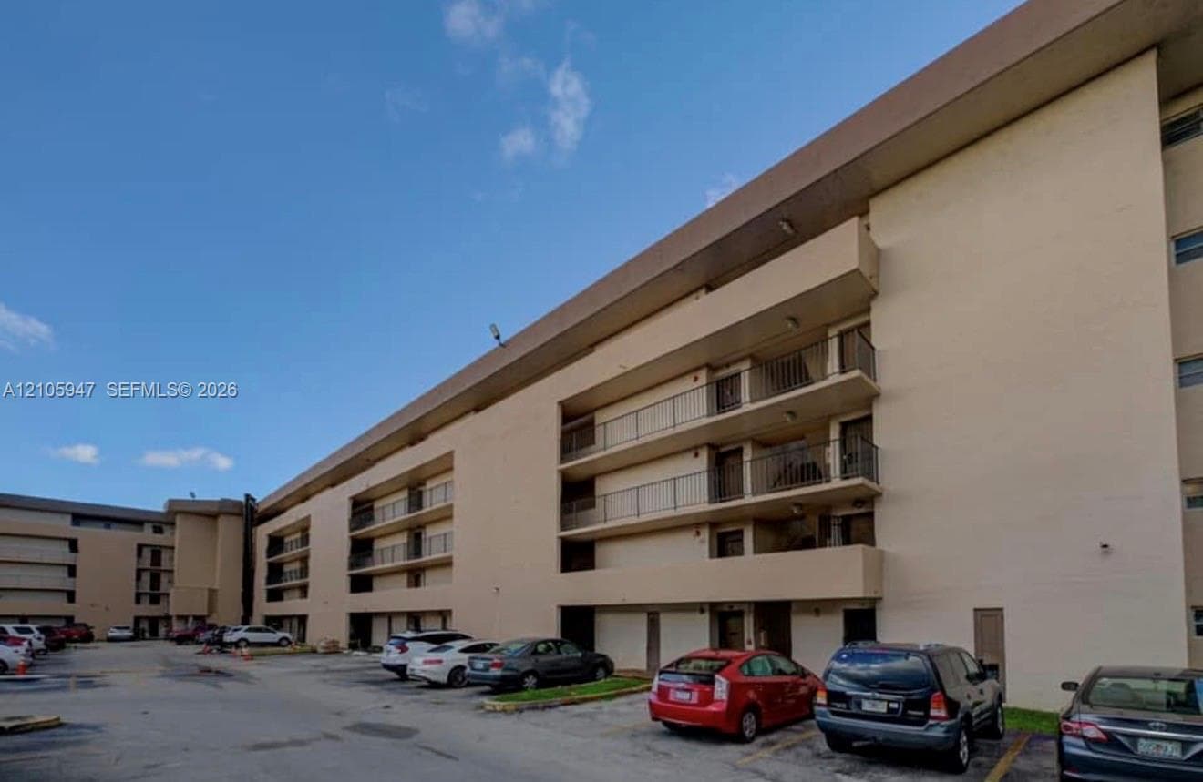Multi-story exterior featuring a neutral stucco facade, overhanging roof eaves, and stacked private balconies with metal railings