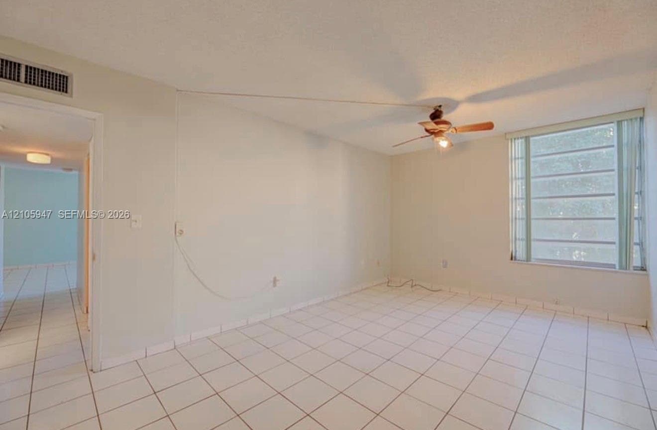Interior space featuring white floor tiles, a ceiling fan with integrated lighting, and a window with horizontal blinds