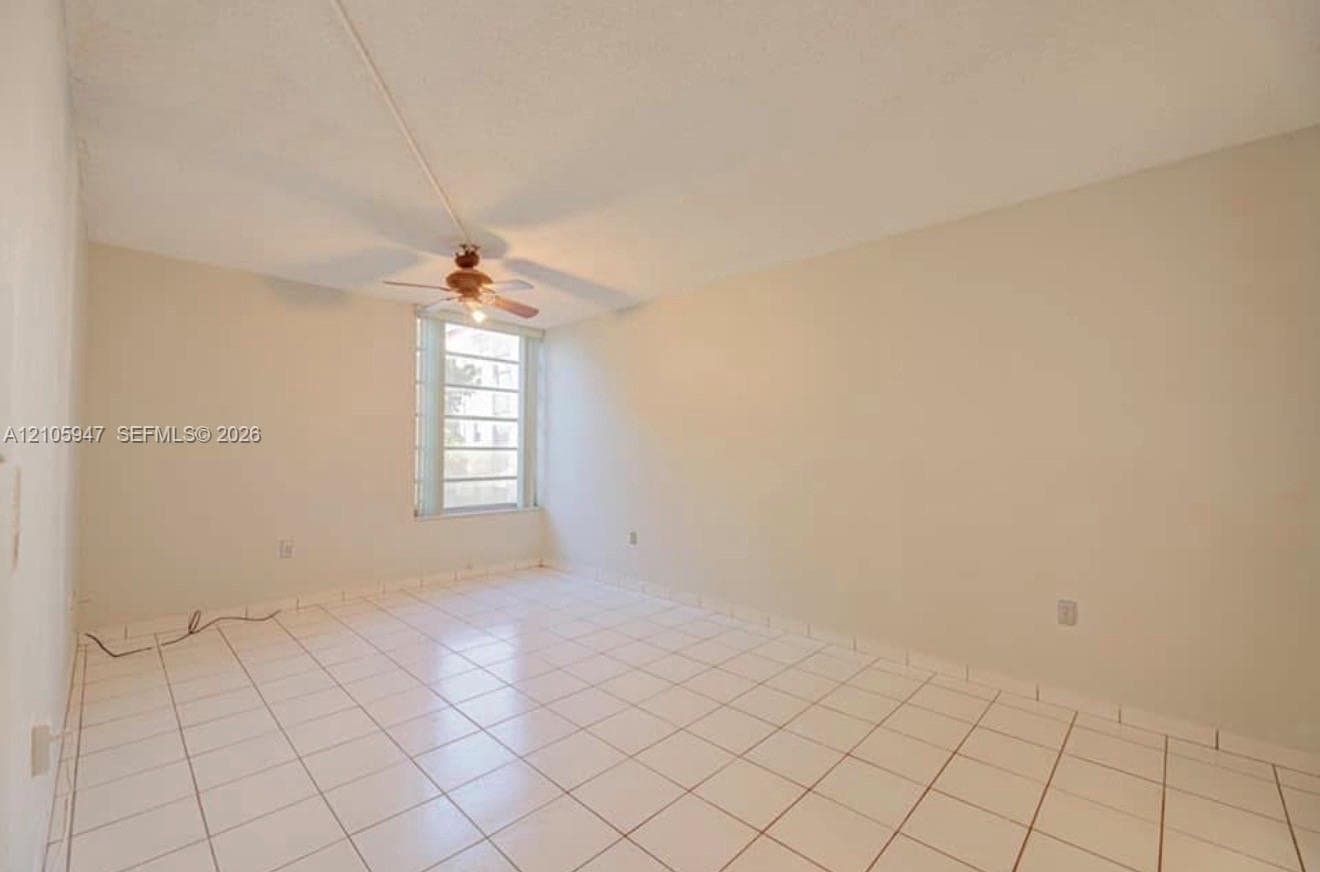 Interior space featuring tile flooring, neutral wall paint, a multi-pane window, and a ceiling fan with integrated lighting