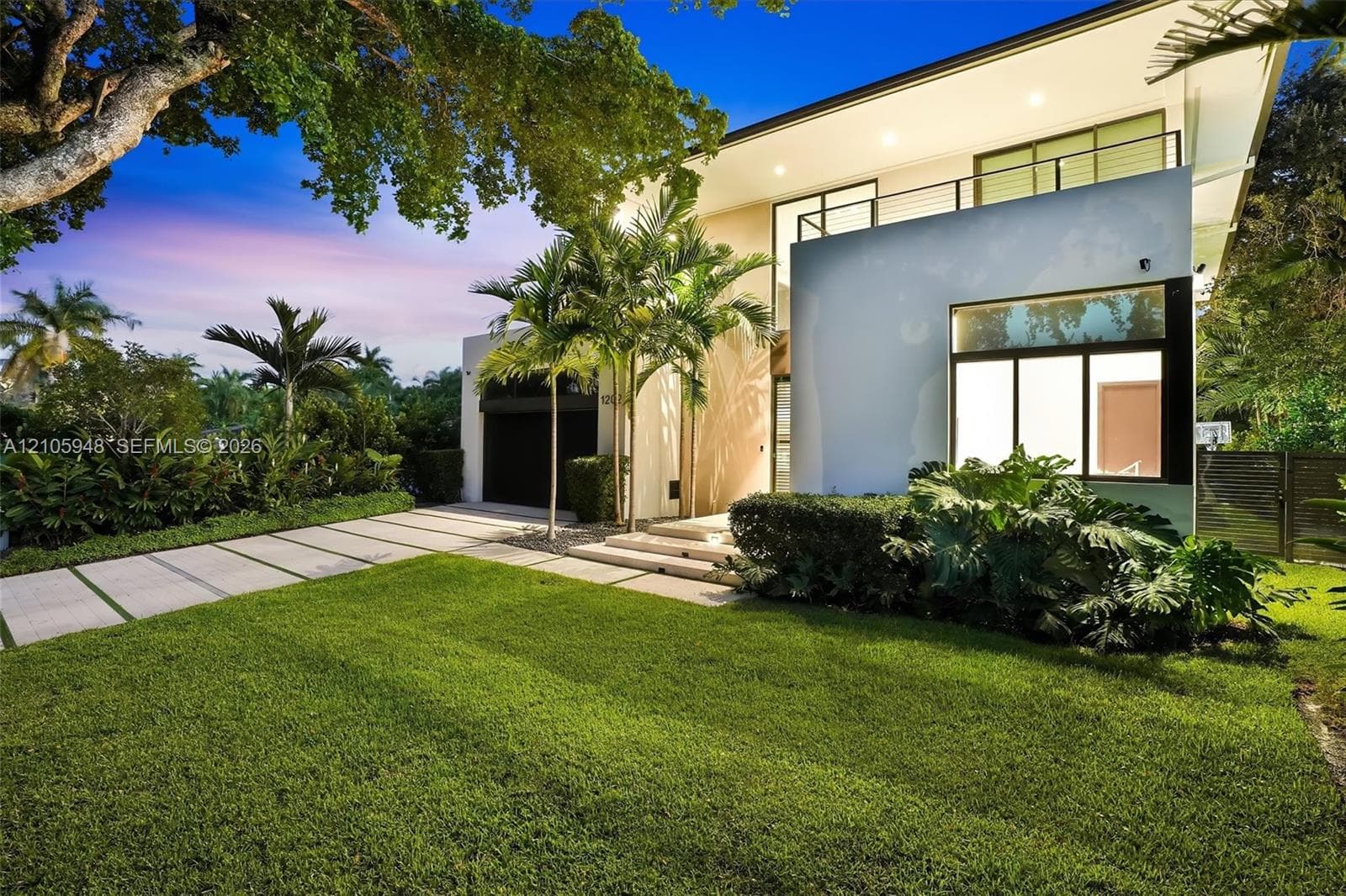 Modern two-story architectural exterior featuring smooth stucco finish, expansive glass windows, an upper-level balcony with metal railing, and a concrete paver driveway