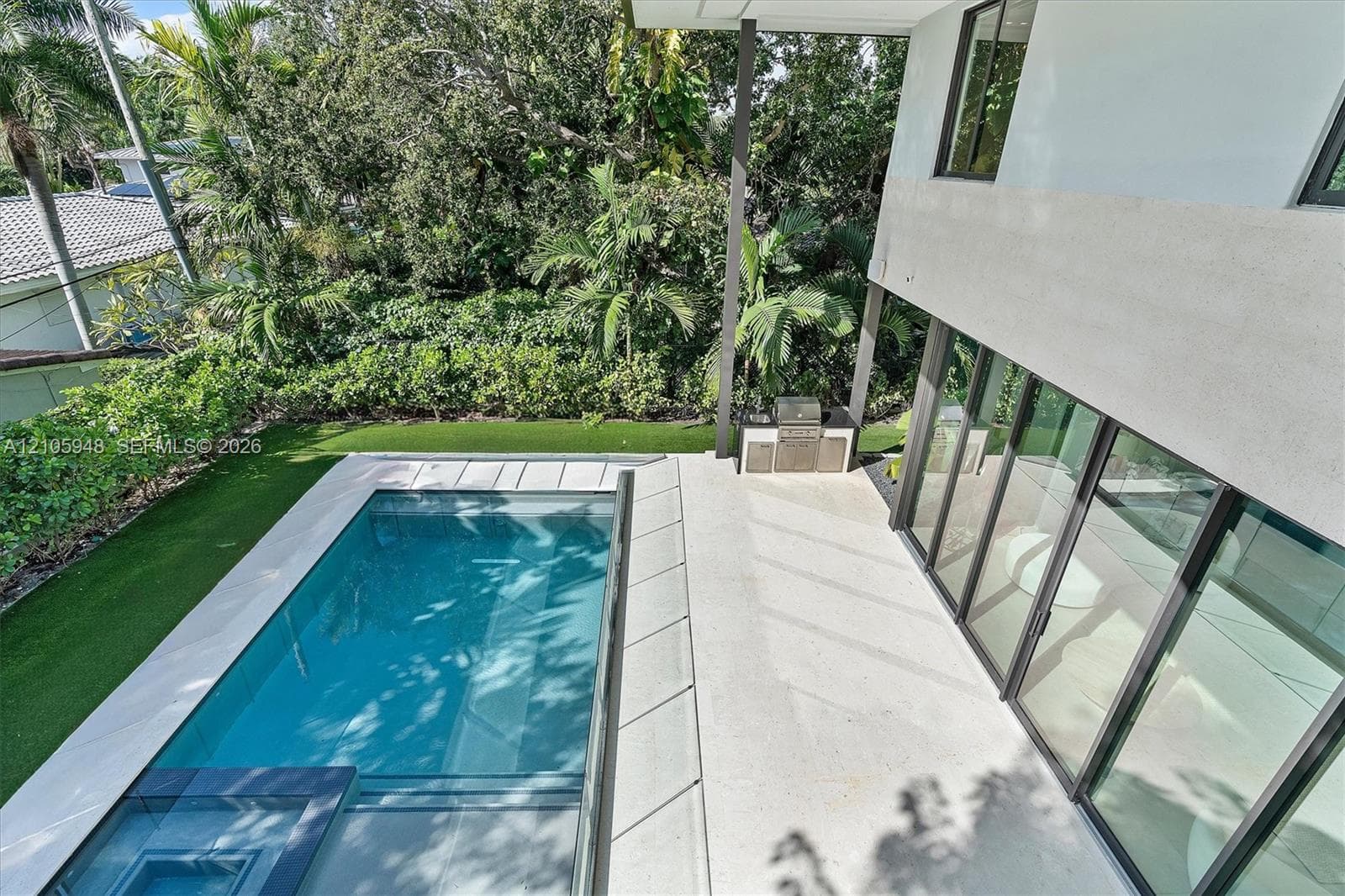 Outdoor area featuring a swimming pool, integrated spa, built-in outdoor kitchen, expansive patio, and synthetic turf lawn