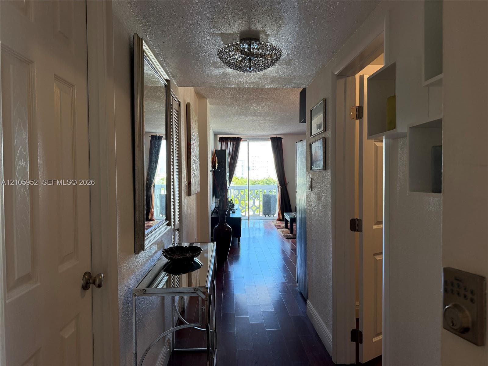 Interior hallway featuring wood-finish flooring, a contemporary semi-flush mount ceiling fixture, and sliding glass doors with access to an exterior balcony