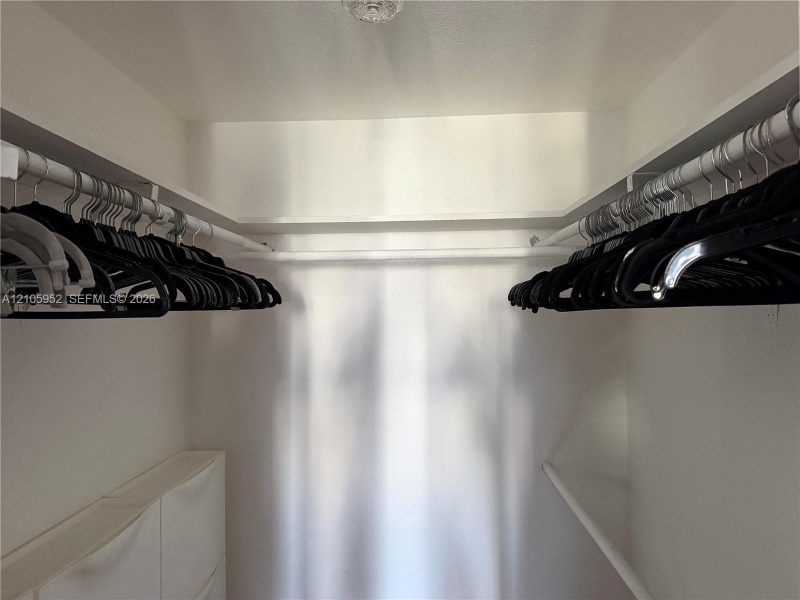 Walk-in storage space featuring wrap-around shelving and dual-tier hanging rods