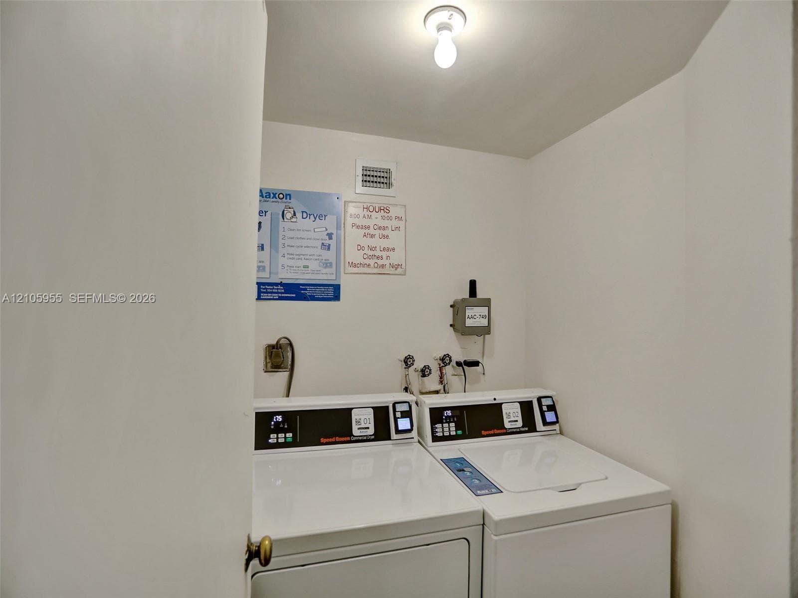 Utility area featuring built-in commercial-grade laundry appliances, wall-mounted water hookups, and surface-mounted ceiling lighting