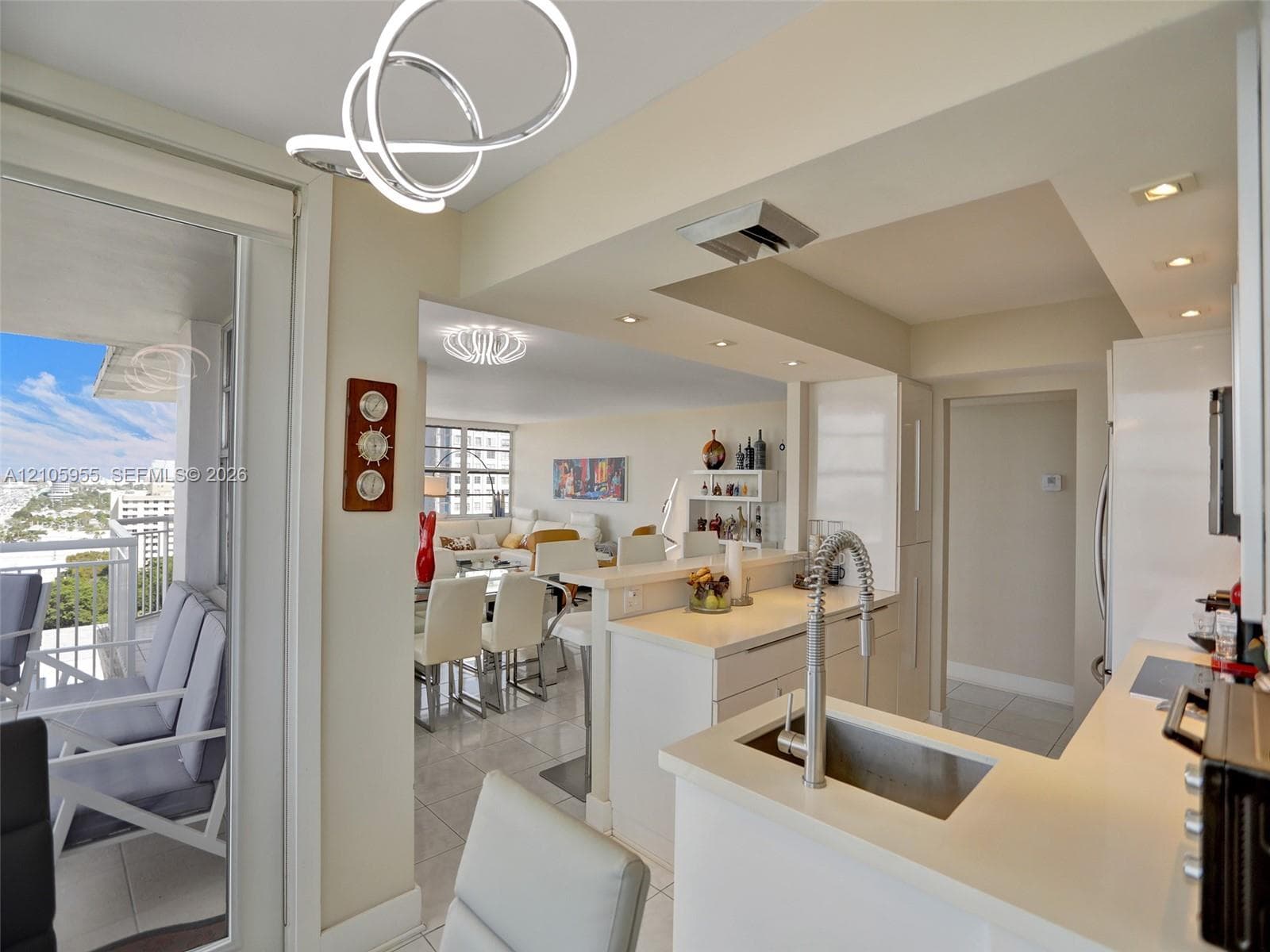 Kitchen featuring a peninsula with a stone-finish countertop, stainless steel undermount sink with a high-arch pull-down faucet, recessed lighting, and sleek white cabinetry