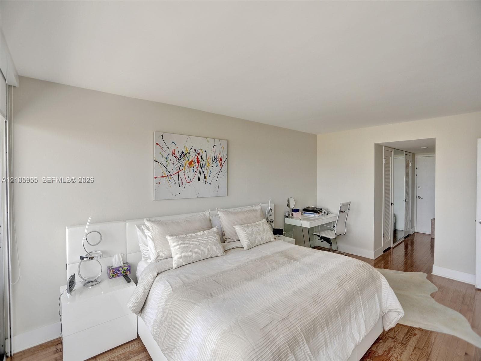 Room featuring wood-finish flooring, neutral wall tones, and floor-to-ceiling mirrored closet doors