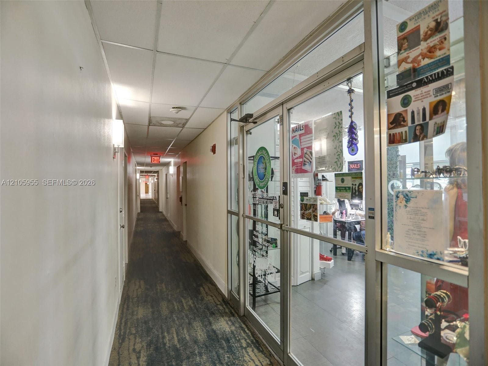Commercial hallway featuring drop-ceiling tiles, recessed lighting, and glass-paneled entry doors with aluminum framing