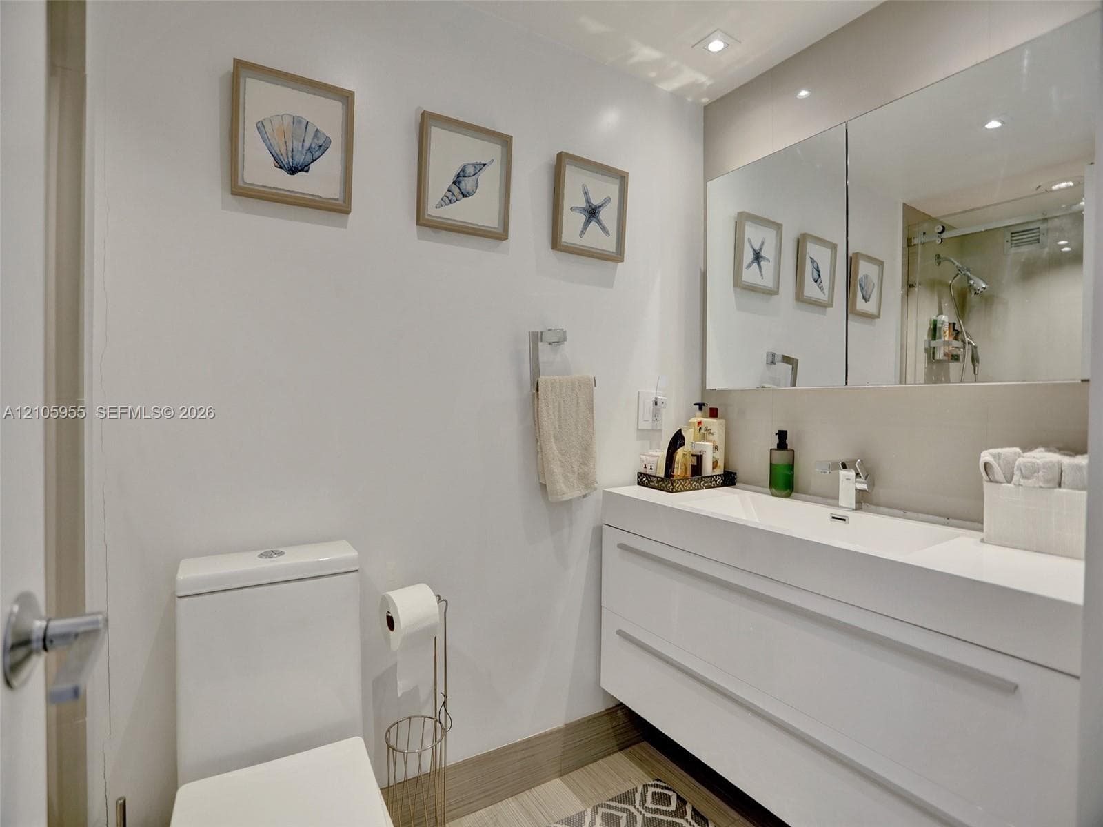 Modern floating vanity featuring an integrated white sink and basin, chrome faucet, expansive wall-to-wall mirror, and recessed lighting