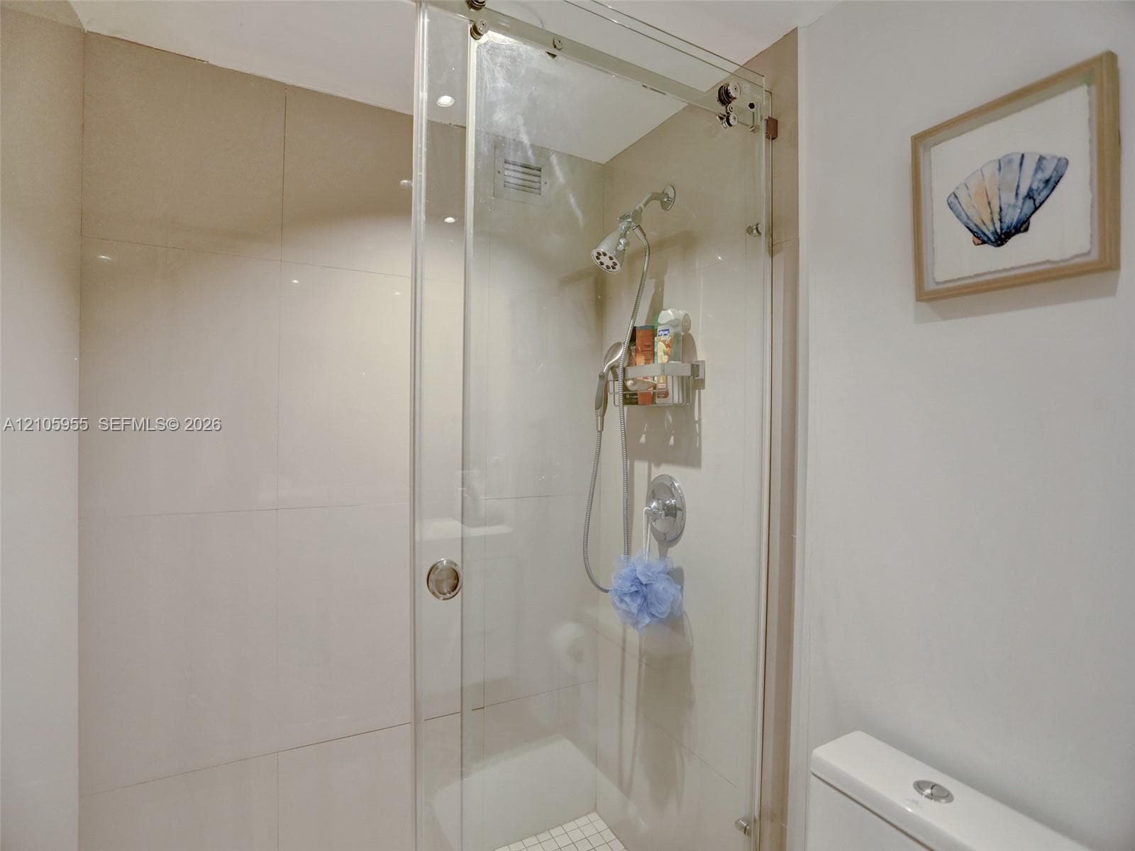 Walk-in shower with floor-to-ceiling tile, frameless glass sliding enclosure, polished chrome rainfall showerhead, and handheld sprayer