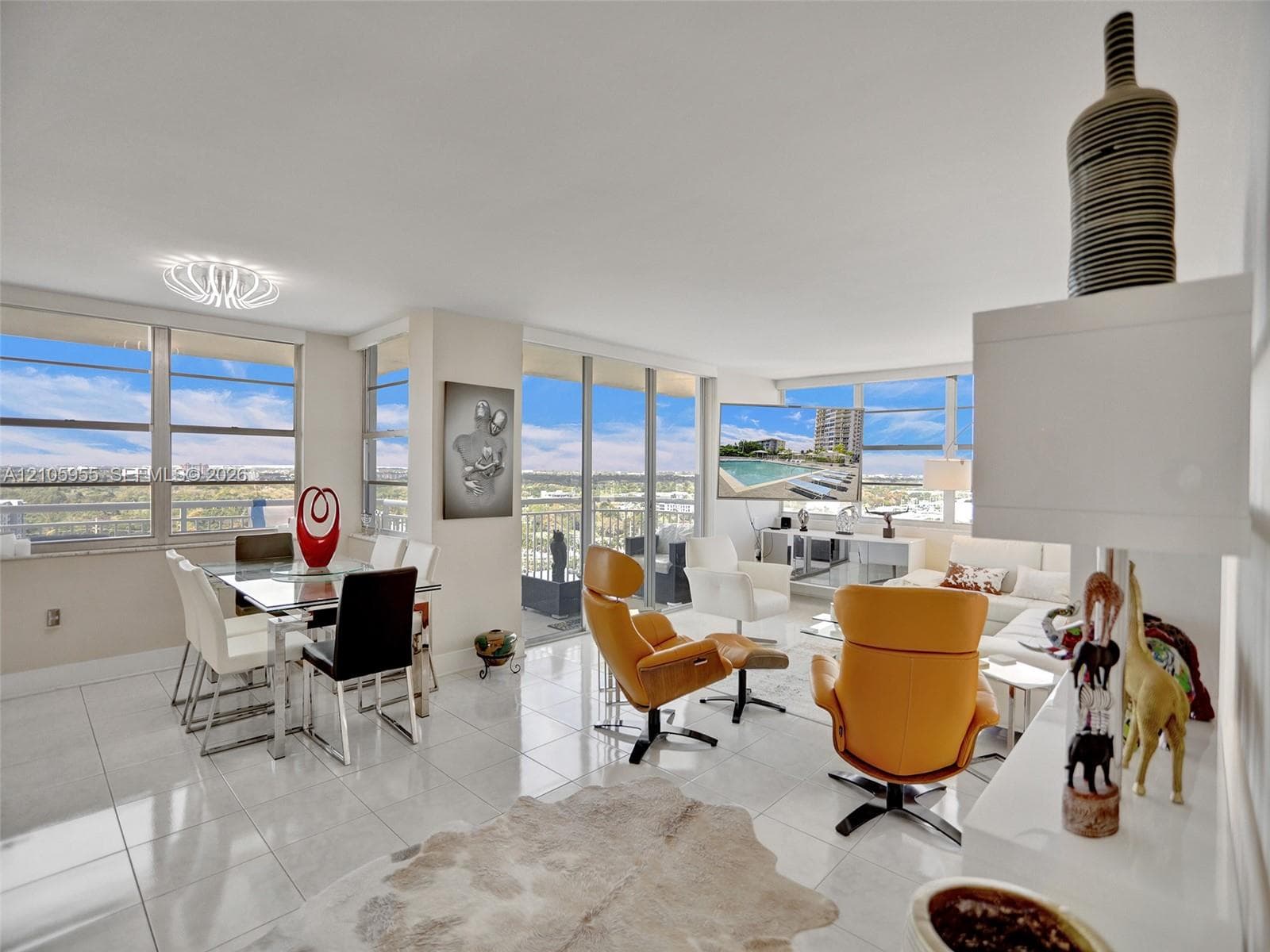 Open-concept interior featuring large-format ceramic tile flooring, floor-to-ceiling windows, a private balcony, and contemporary overhead lighting