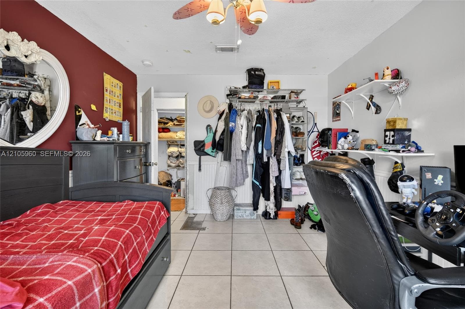 Room featuring large-format tile flooring, accent wall, and built-in closet storage