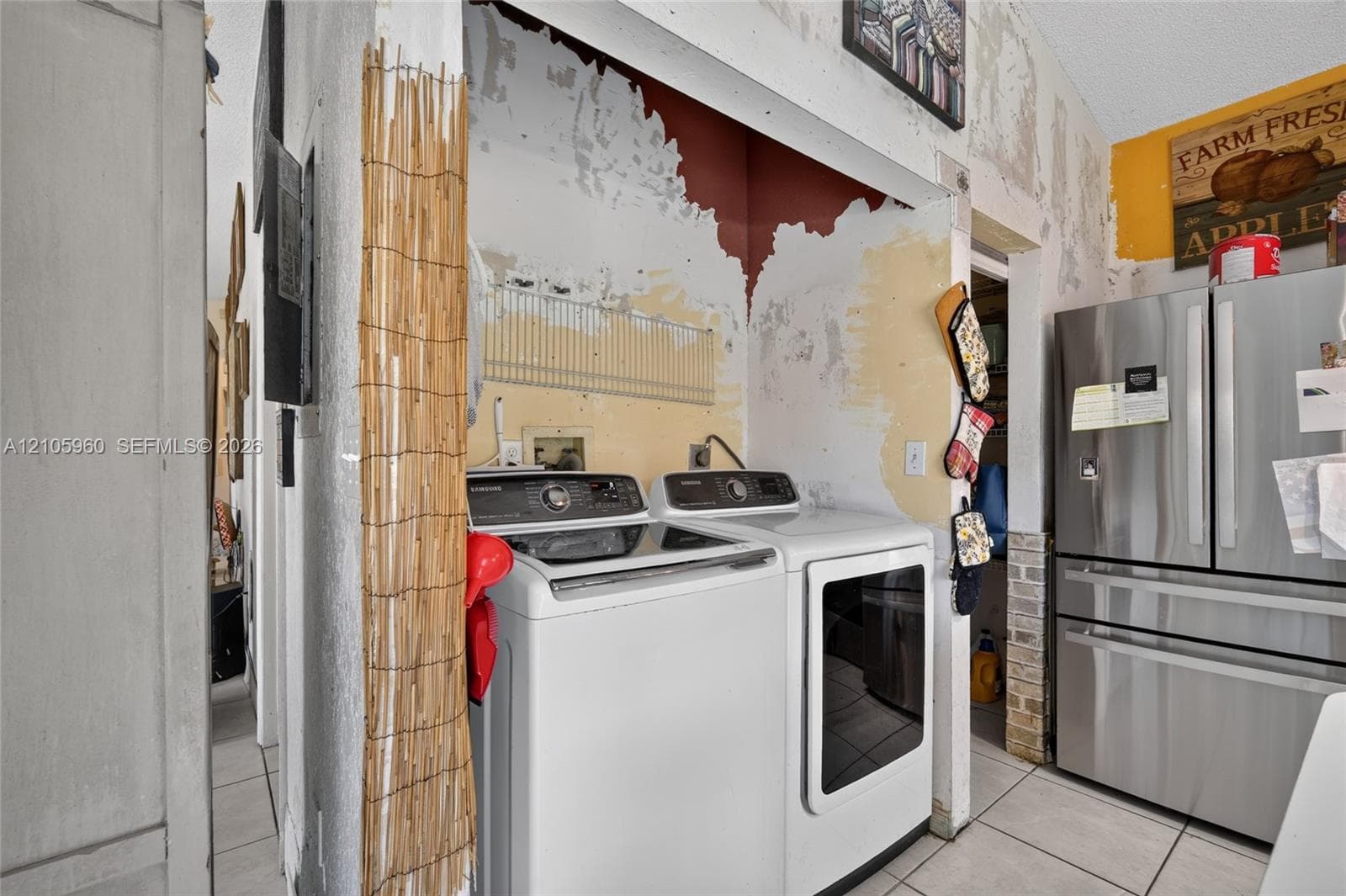 Laundry area featuring tile flooring, built-in wire shelving, and a stainless steel french-door refrigerator
