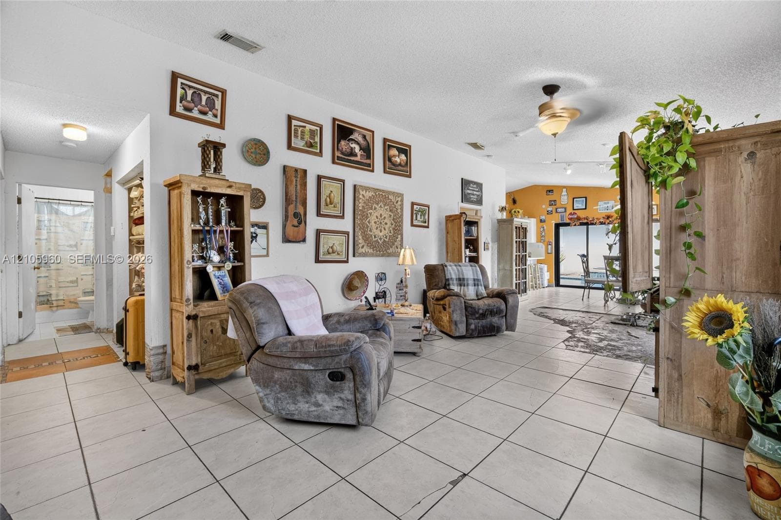 Neutral tile flooring, ceiling fan with integrated lighting, and large sliding glass door