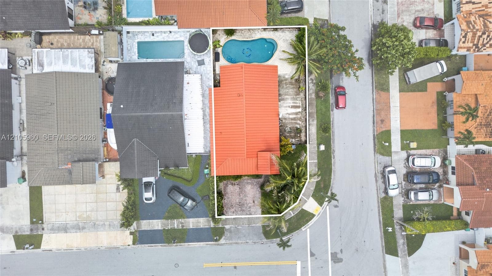 Aerial perspective featuring a prominent orange tile roof, in-ground swimming pool, and paved exterior space