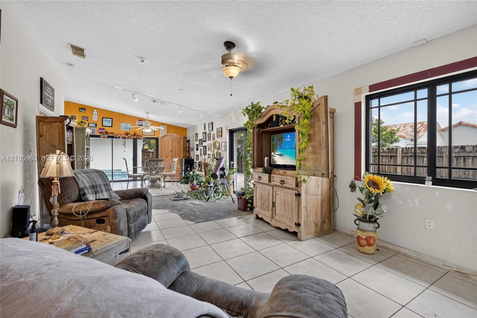 Open-concept interior featuring large-format tile flooring, multi-pane black-frame windows, and a ceiling fan with integrated lighting