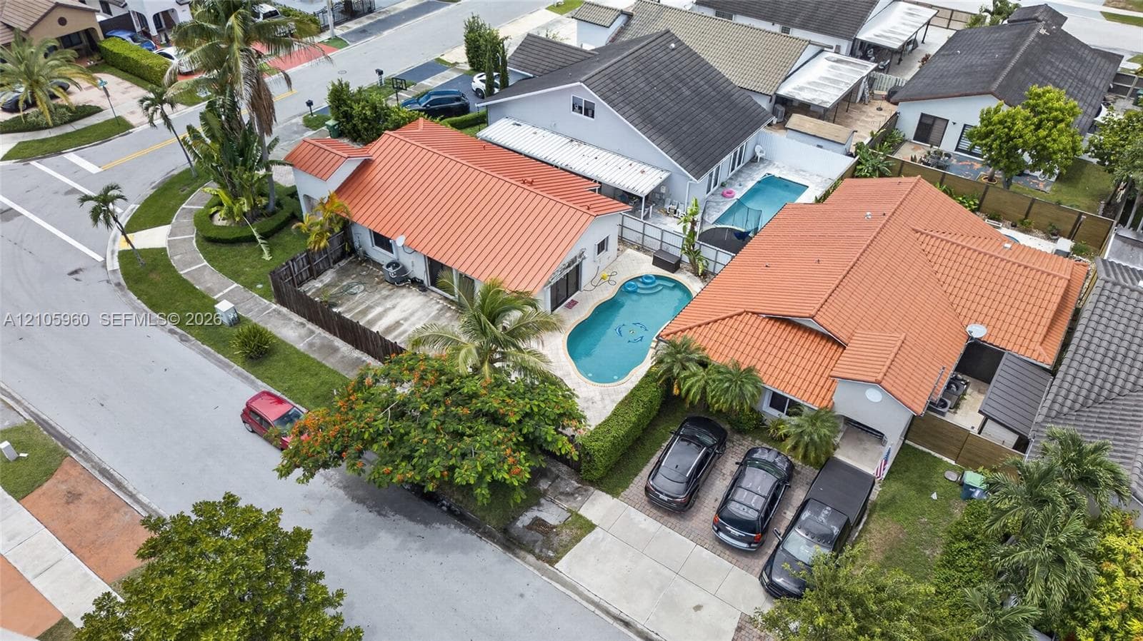 Single-story residence featuring a standing-seam metal roof, private in-ground pool, hardscaped patio, and a concrete driveway