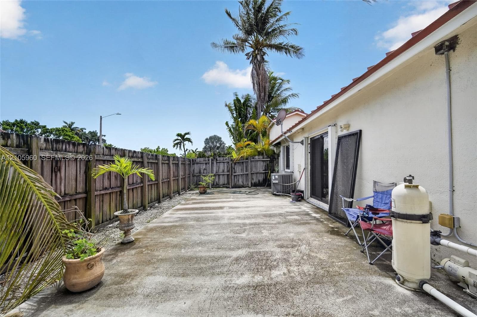 Concrete patio area enclosed by a wood privacy fence and featuring sliding glass doors