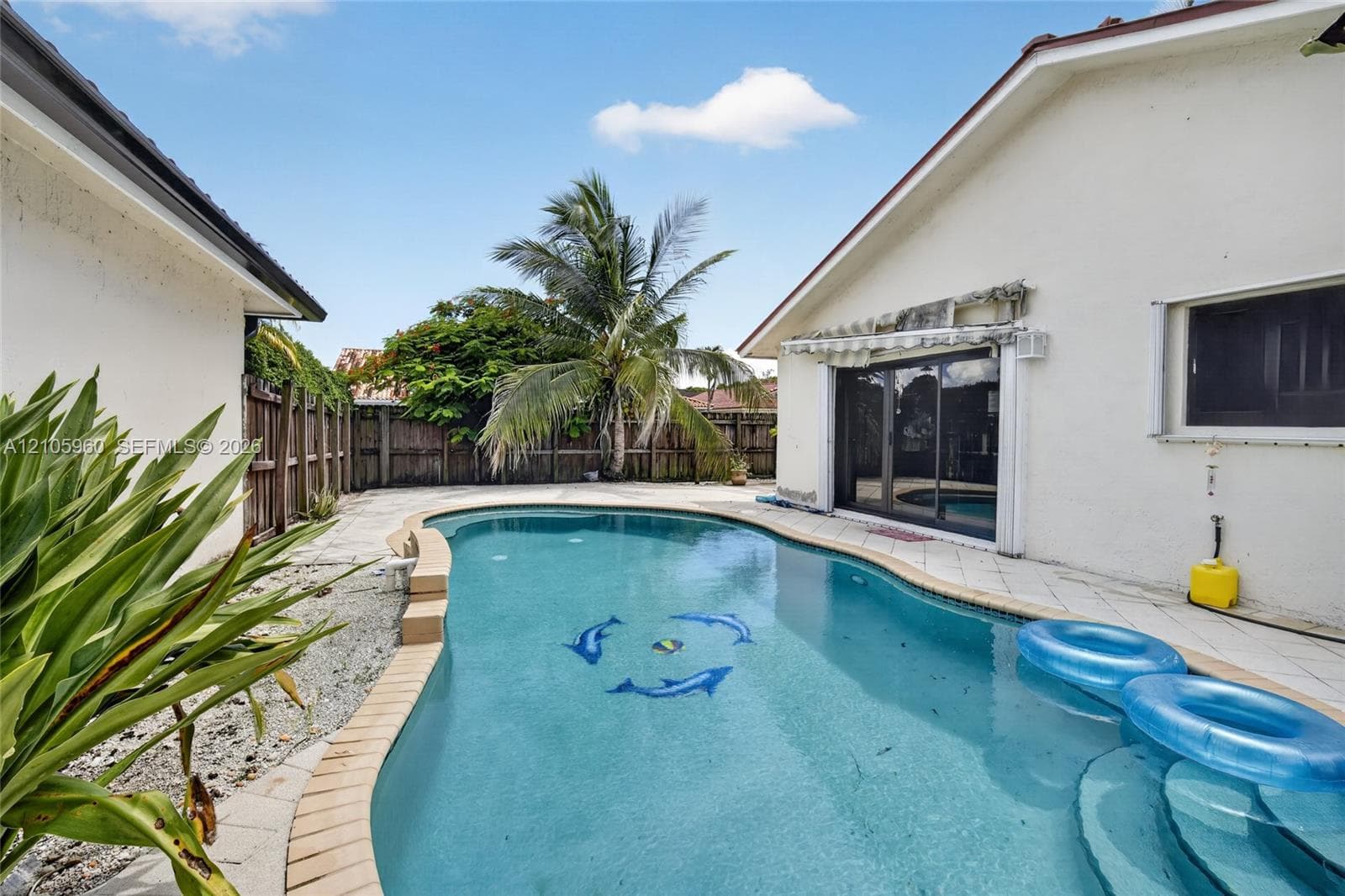 In-ground swimming pool with tile trim, concrete patio surround, and wood privacy fencing