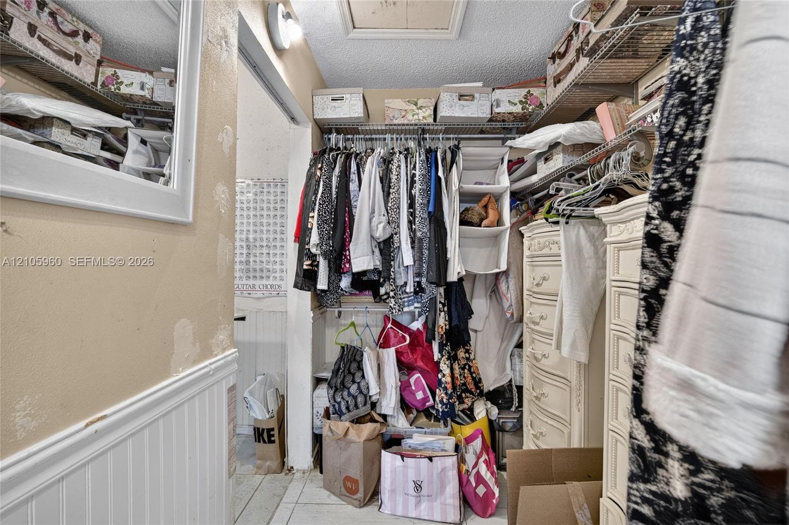 Walk-in closet featuring tiered wire shelving and lower wainscoting