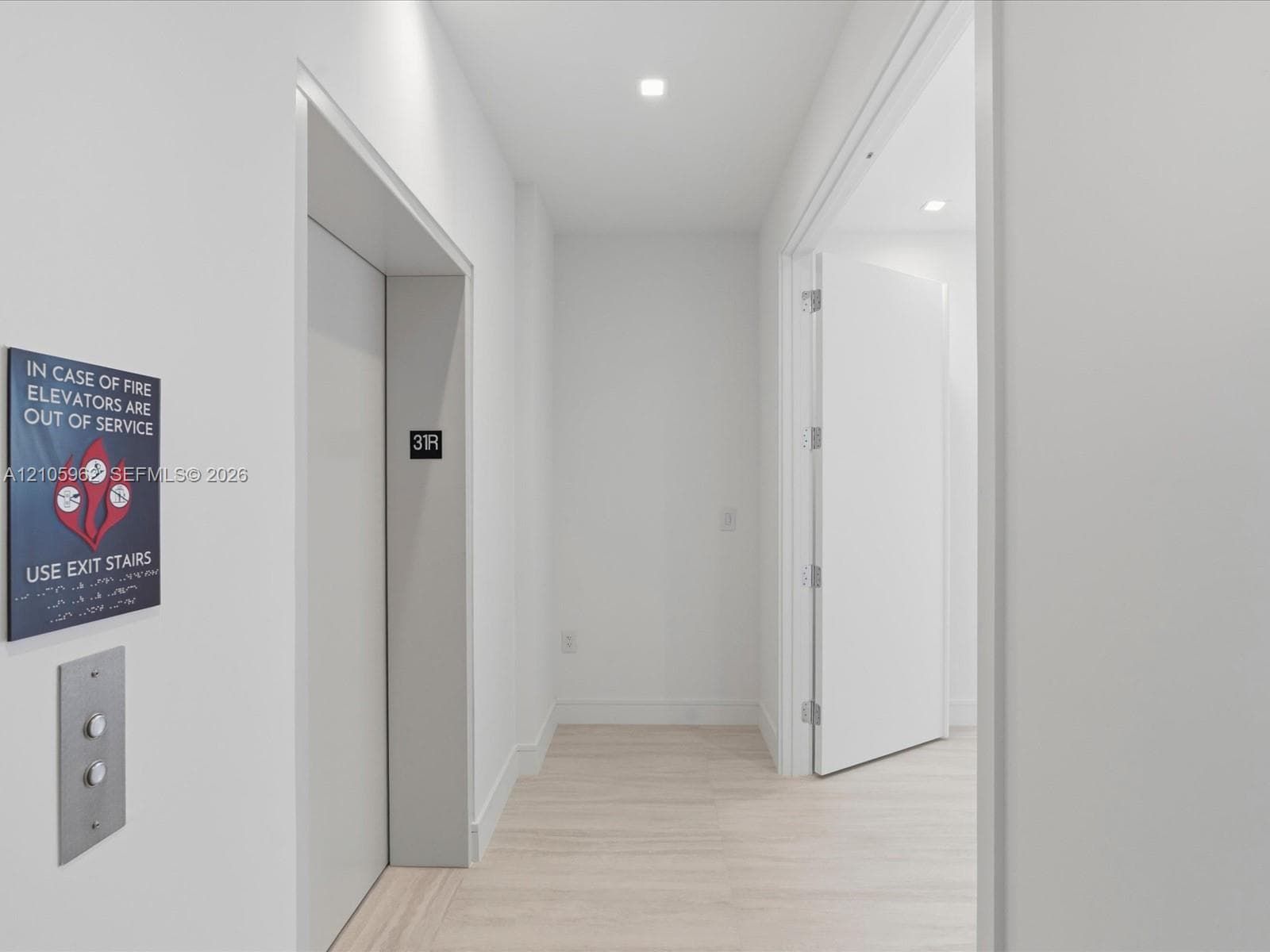 Hallway featuring recessed ceiling lighting, wood-finish flooring, and a private elevator access point