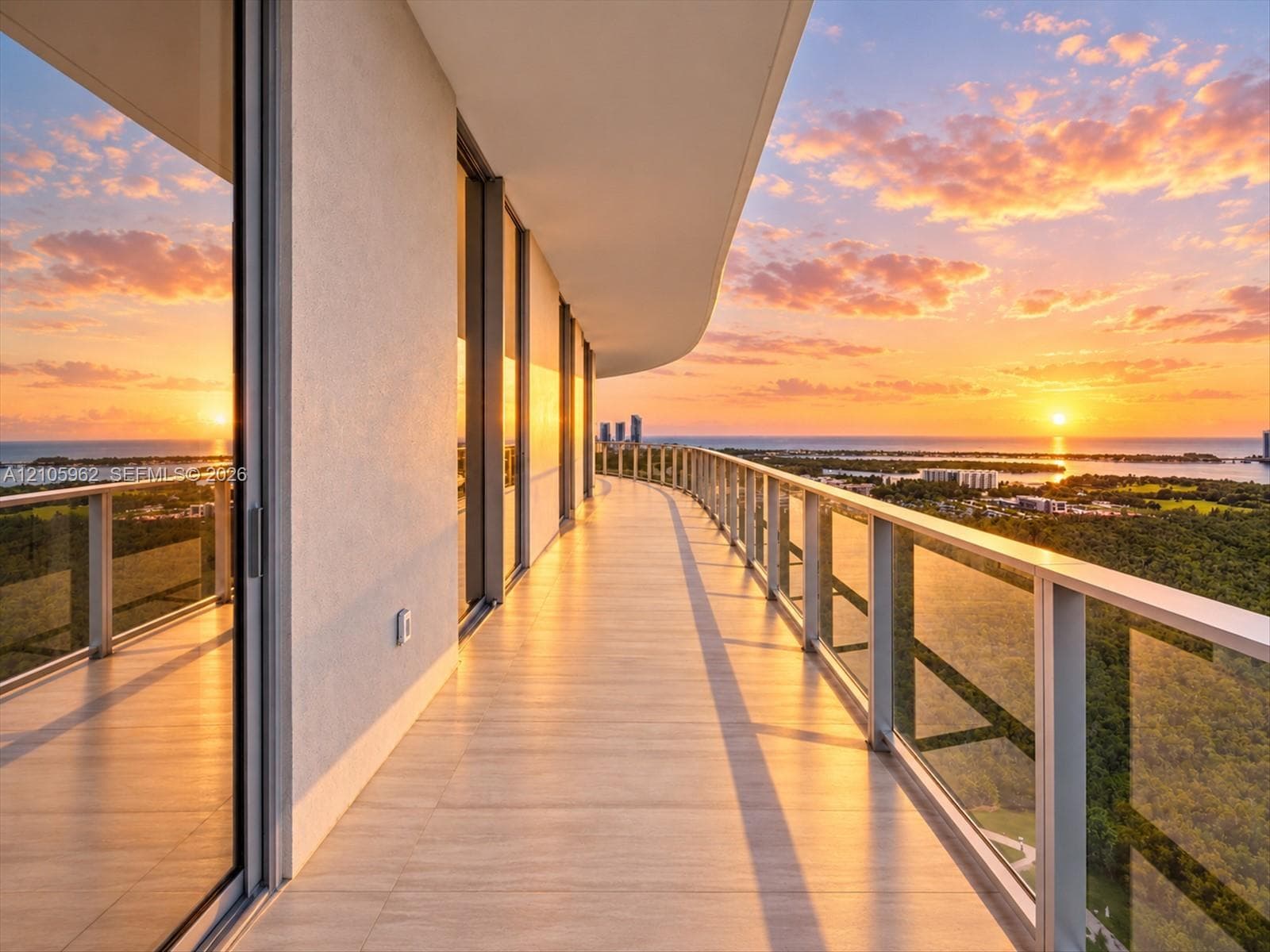 Expansive wrap-around balcony featuring floor-to-ceiling glass doors, large-format tile flooring, and a sleek metal railing system