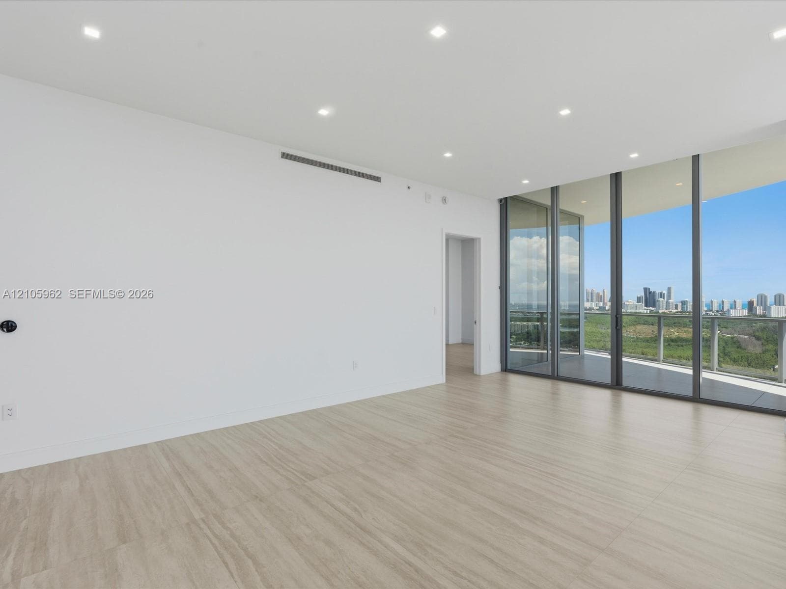 Interior space featuring neutral wall-finish, recessed lighting, wood-finish flooring, floor-to-ceiling glass wall, and balcony access