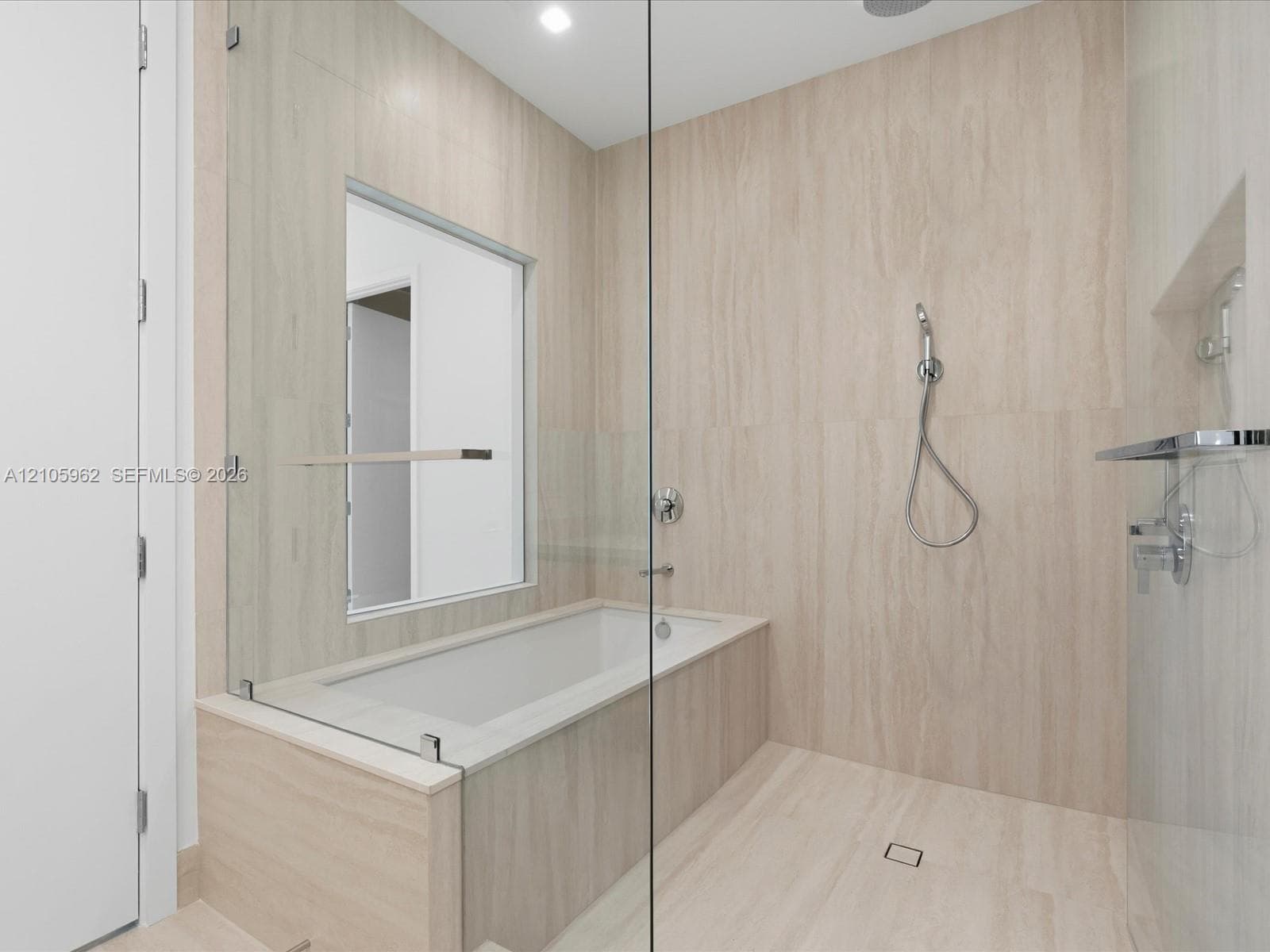 Walk-in shower and tub combination featuring floor-to-ceiling stone-finish tiling, a frameless glass enclosure, polished chrome fixtures, and a hand-held shower wand